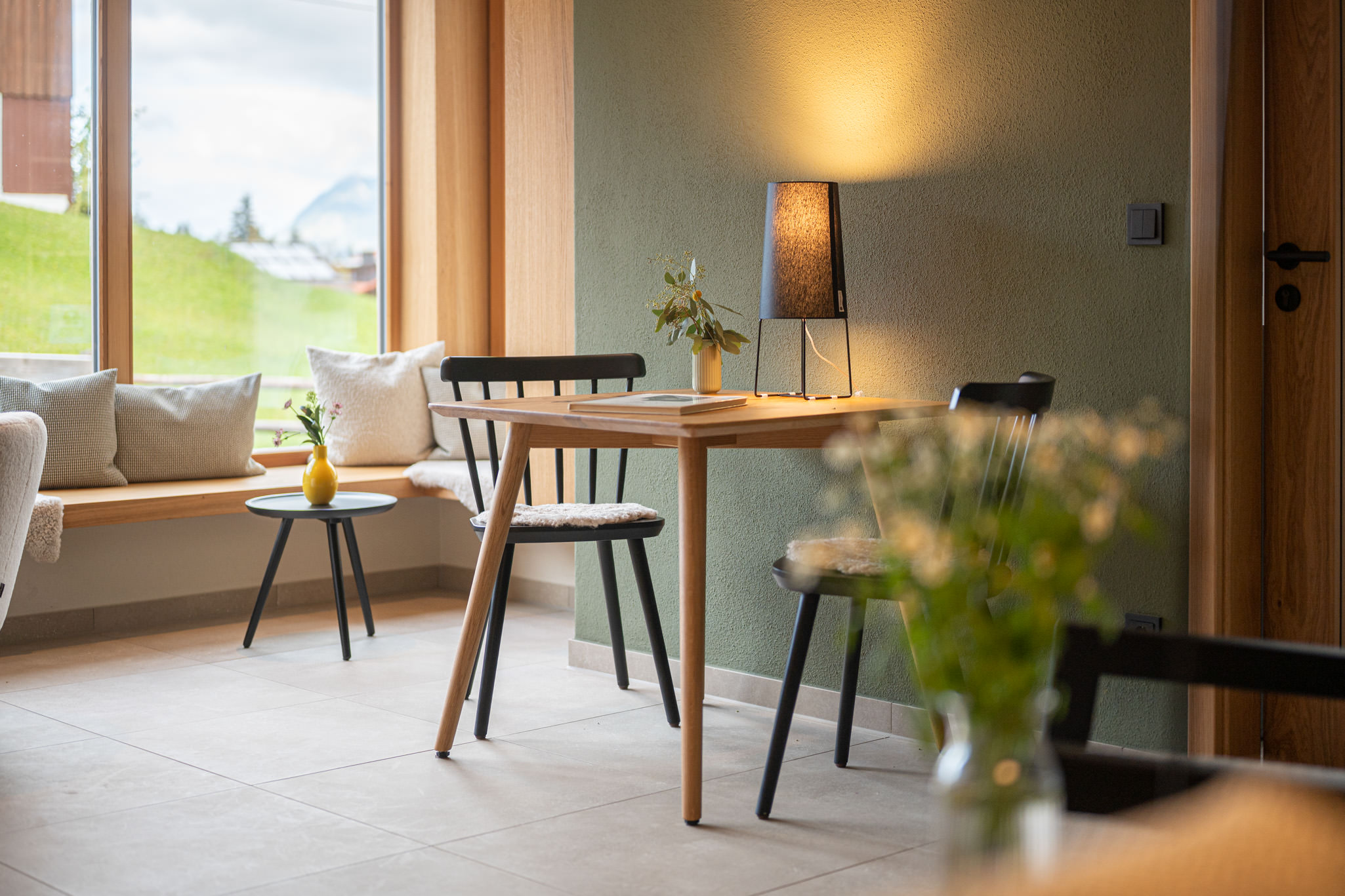 Tisch mit Stühle in Ferienwohnungen MAISEL Ein gemütlicher Tisch aus Holz mit zwei Stühlen. Auf dem Tisch steht eine Lampe und ein kleines Blumenarrangement.