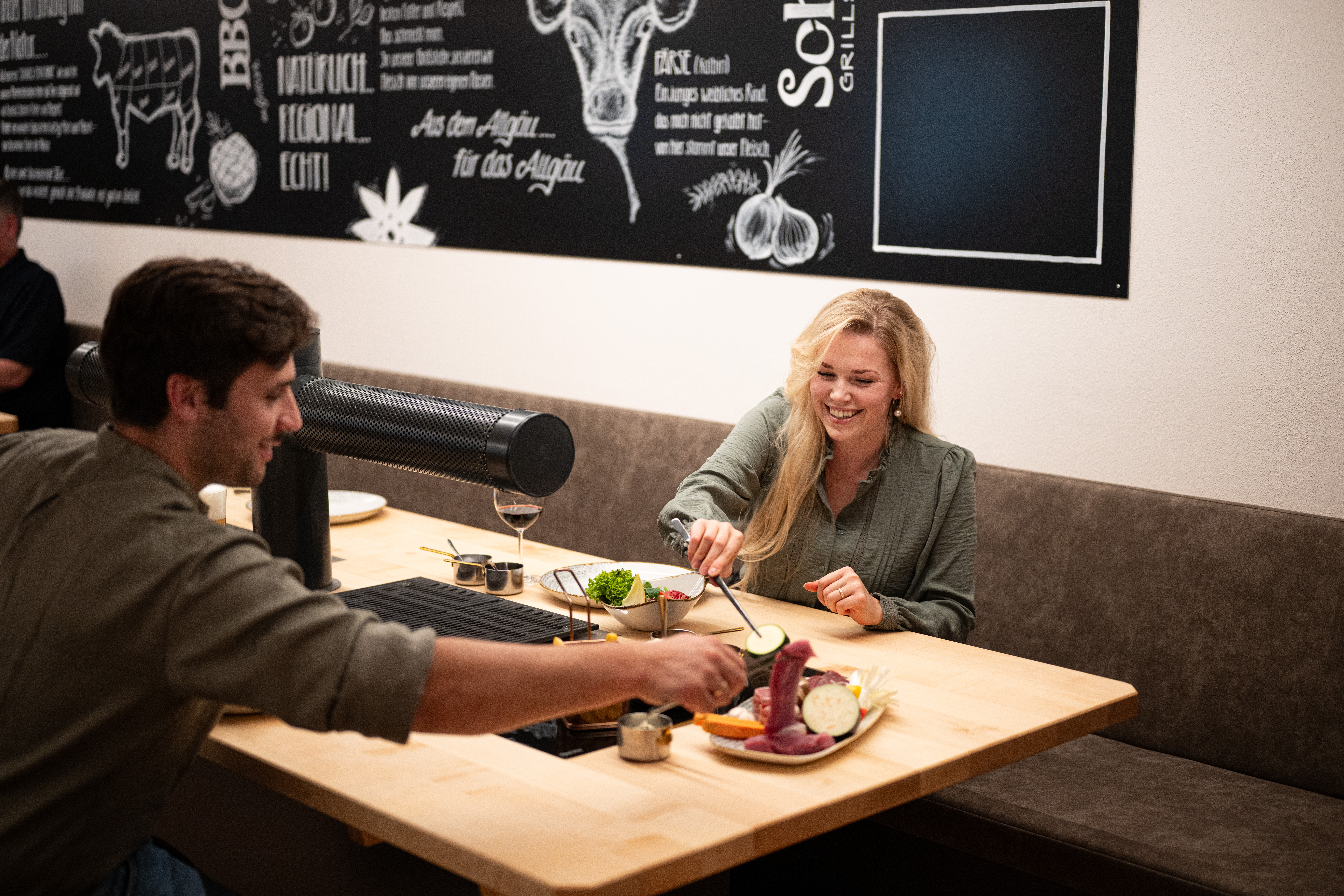 Pärchen am Tischgrill, Fleisch, Gemüse, Pommes Frites, Ofenkartoffel und verschiedenen Soßen