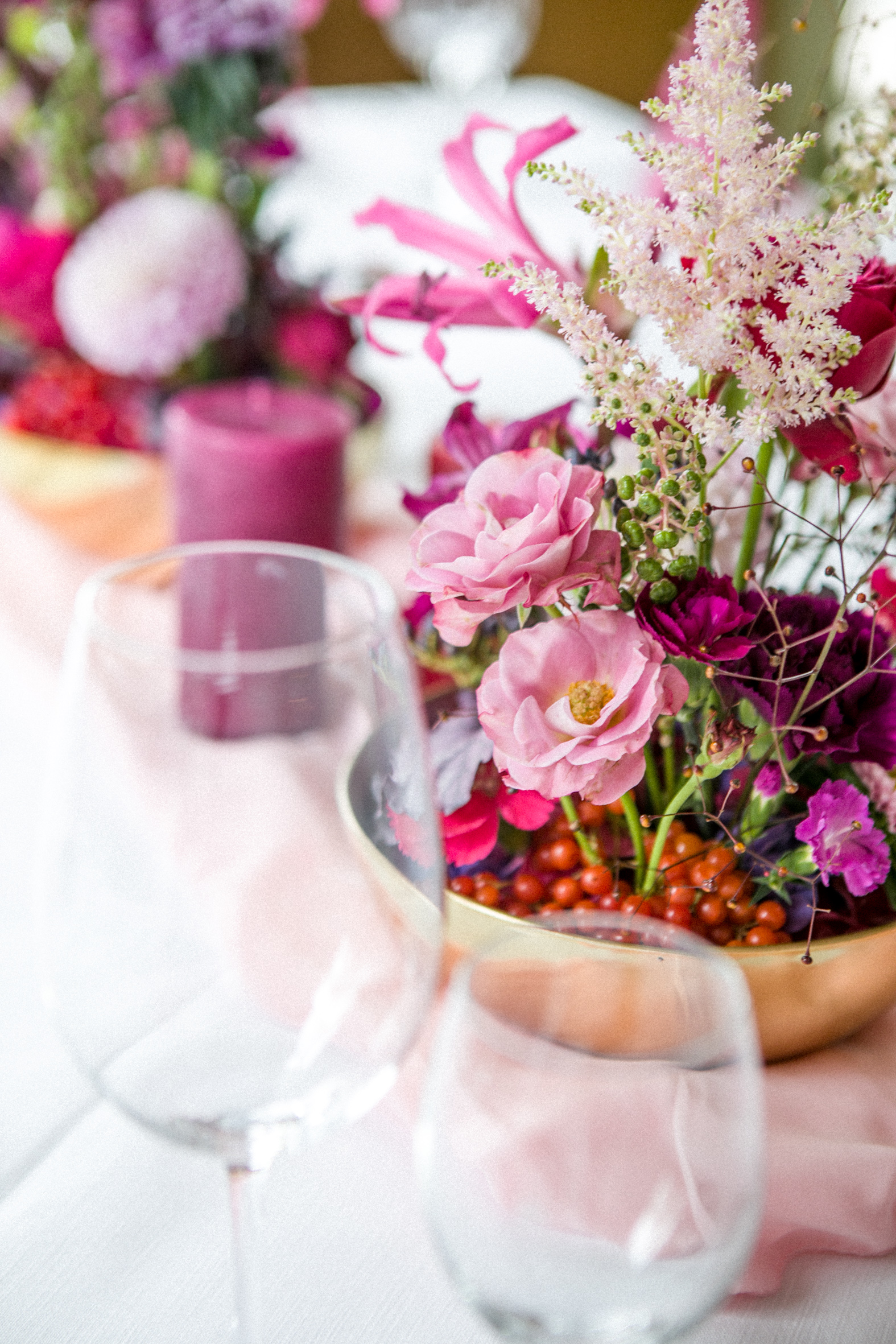 Blumengesteck auf gedeckten Tisch Blumengesteck, Kerze und Weingläser auf gedecktem Tisch.