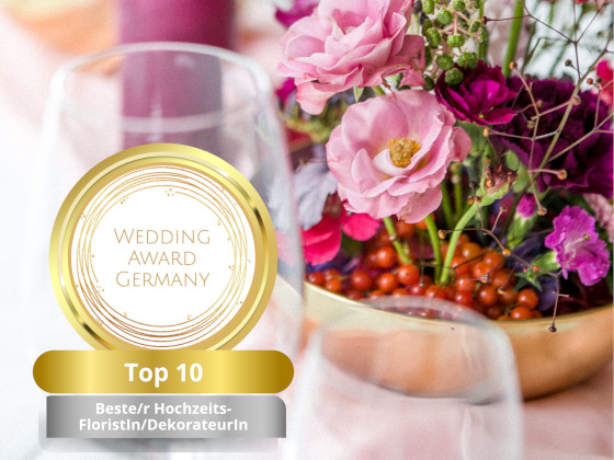 Blumengesteck und Gläser auf Brauttisch, im Vordergrund Logo vom Wedding Award Top 10