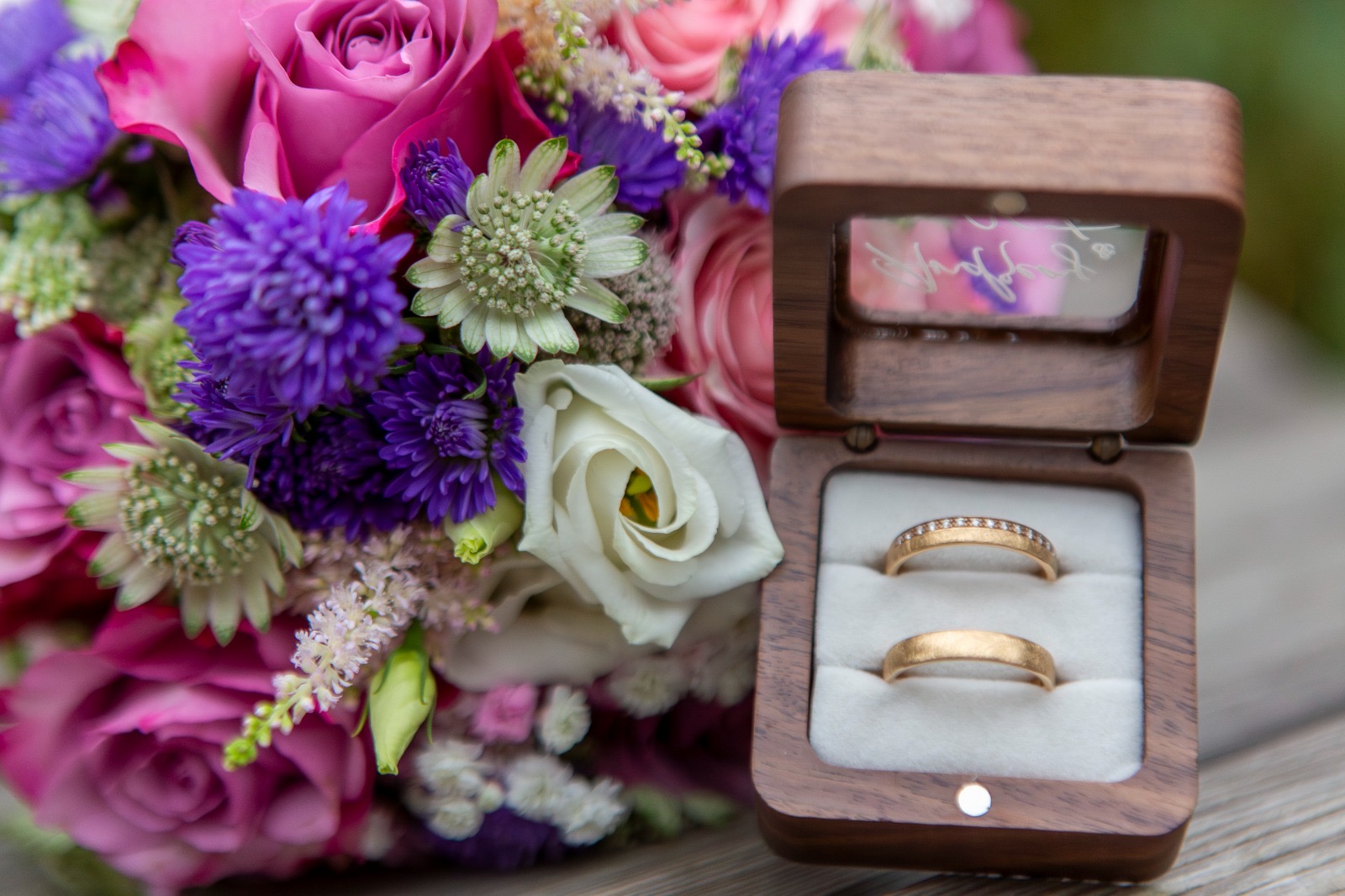 Brautstrauß und Eheringe auf Holztisch in den Hörnerdörfern im Allgäu.