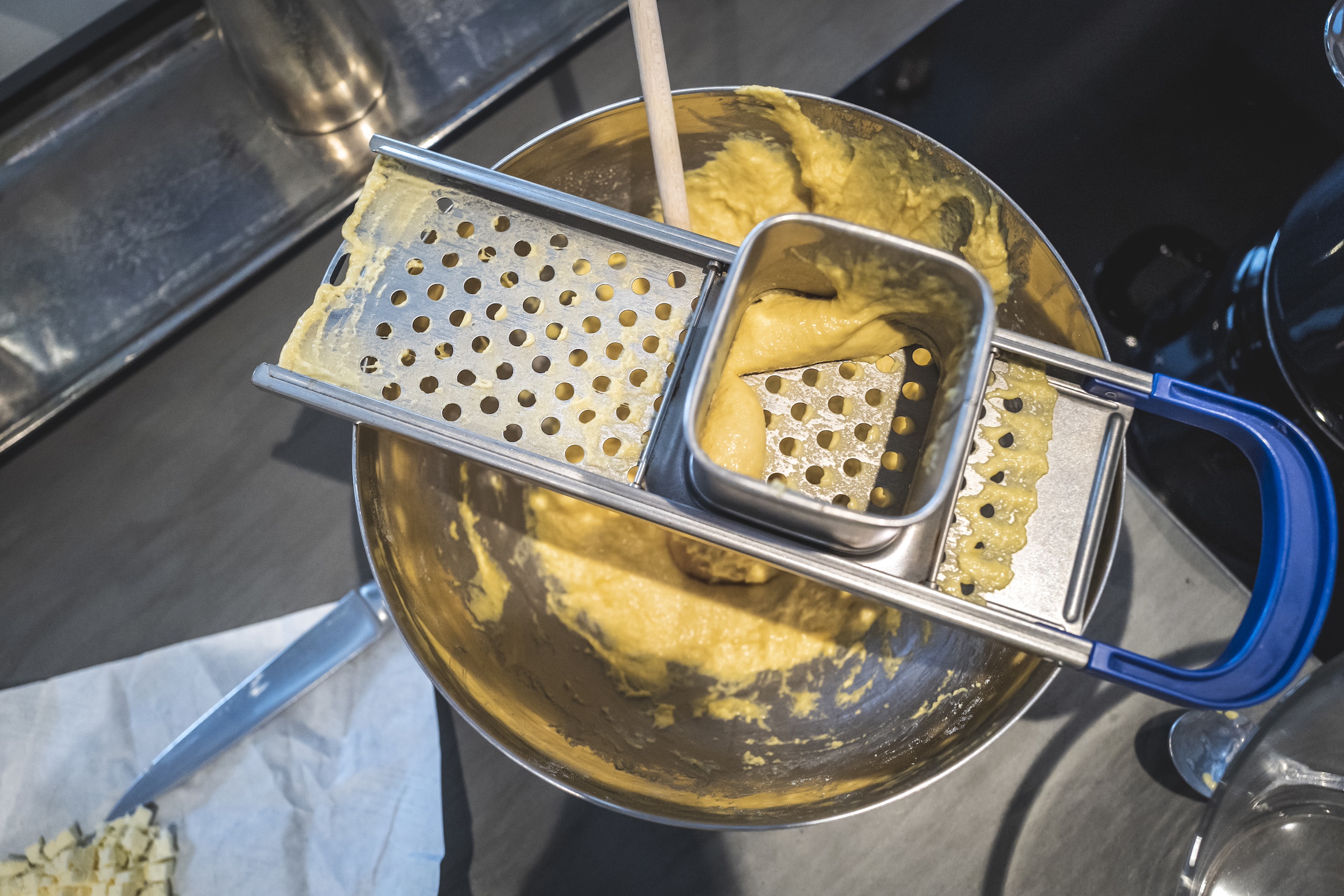 Spätzle reiben Teig in Spätzlereibe füllen und reiben - Hörnerdörfer im Allgäu