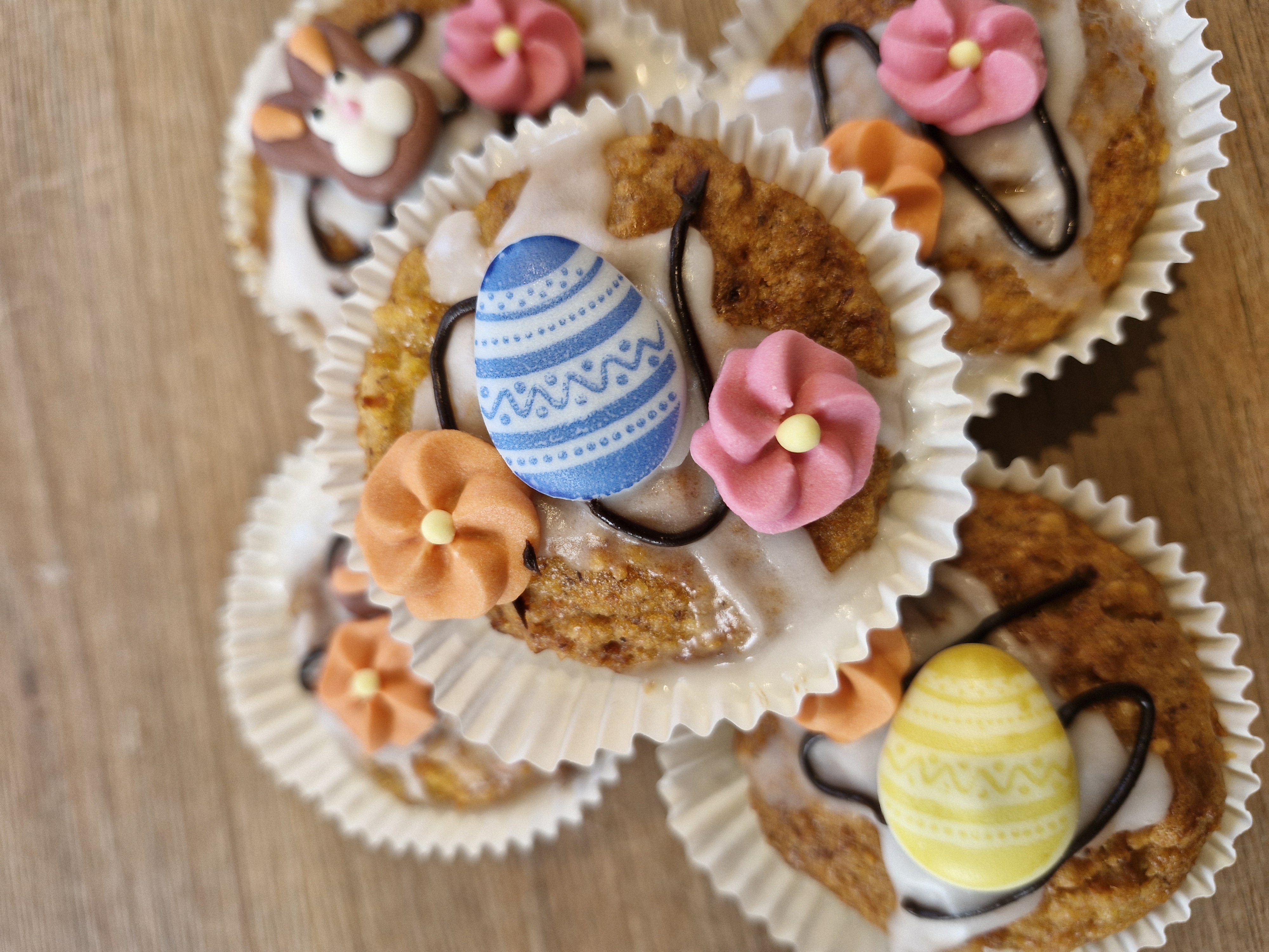 Selbstgebackenen Oster-Muffins, die liebevoll dekoriert auf einer Holzoberfläche arrangiert sind.