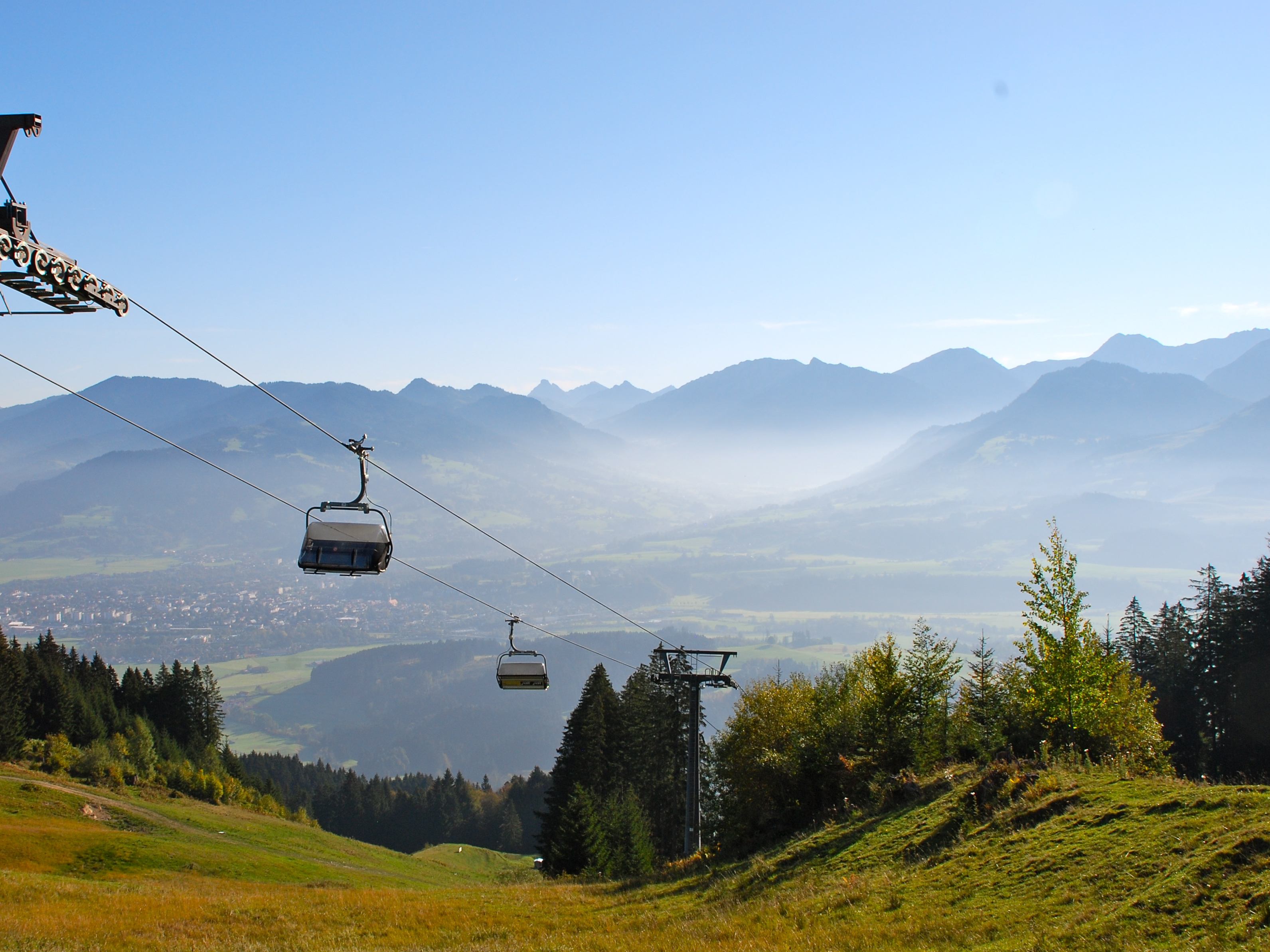 Sessellift in Ofterschwang im Herbst, grüne Wiese, Bäume und Nebel