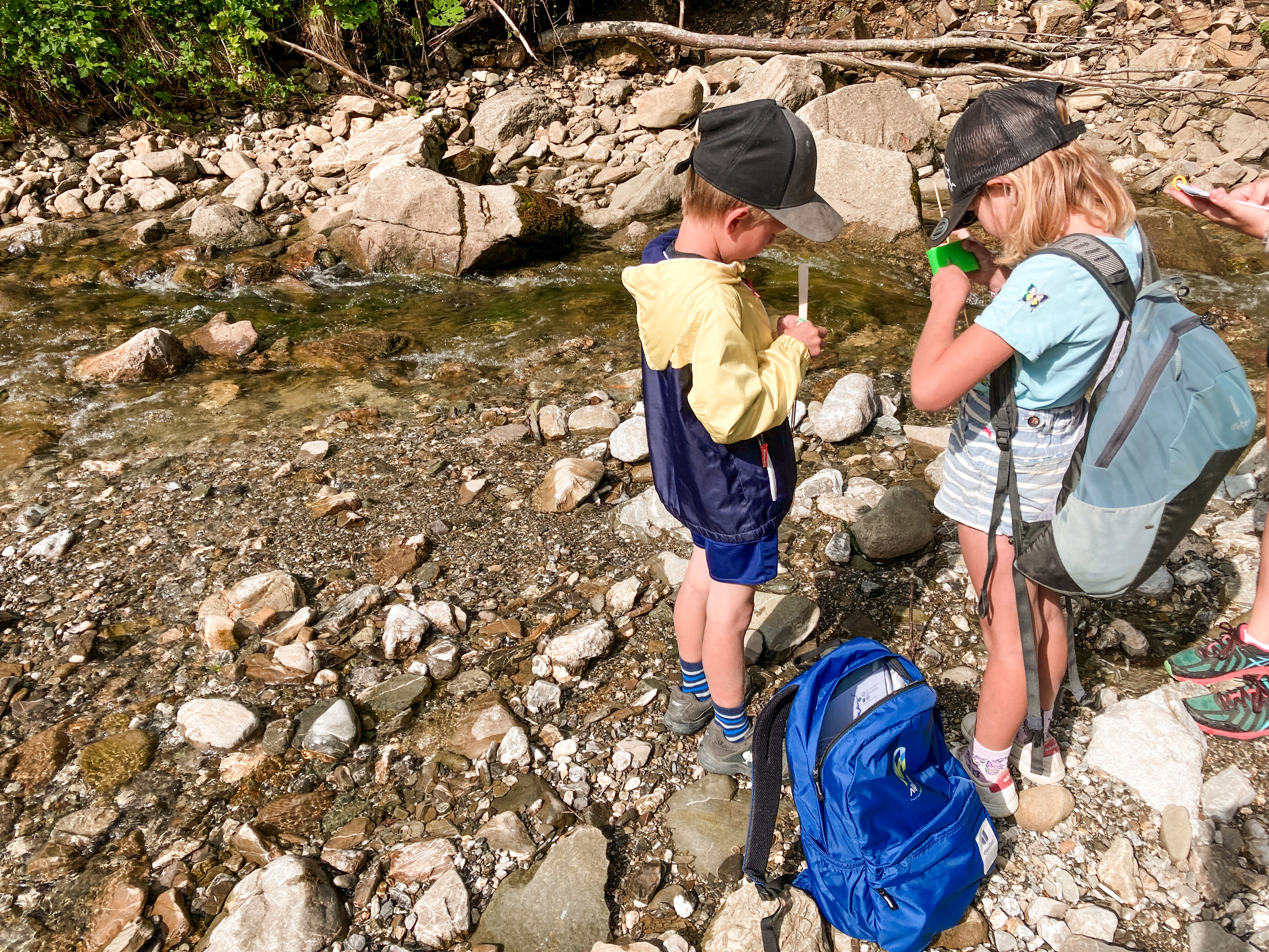 Zwei Kinder experimentieren und bauen ein Wasserrad am Fluss, der Bolgenach, in Balderschwang.