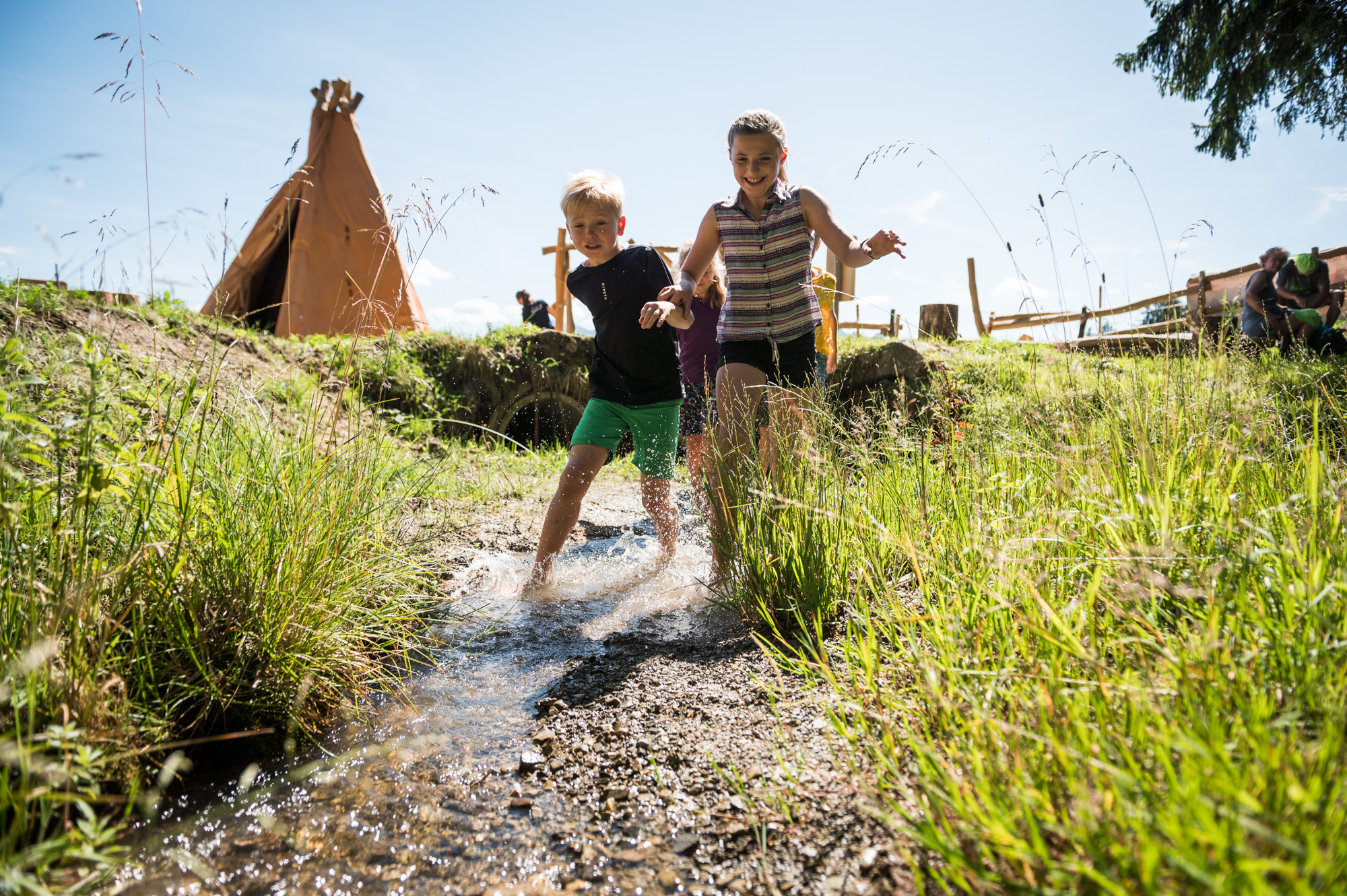 Kinder rennen durch den Bach im Steinzeitdorf in Bolsterlang