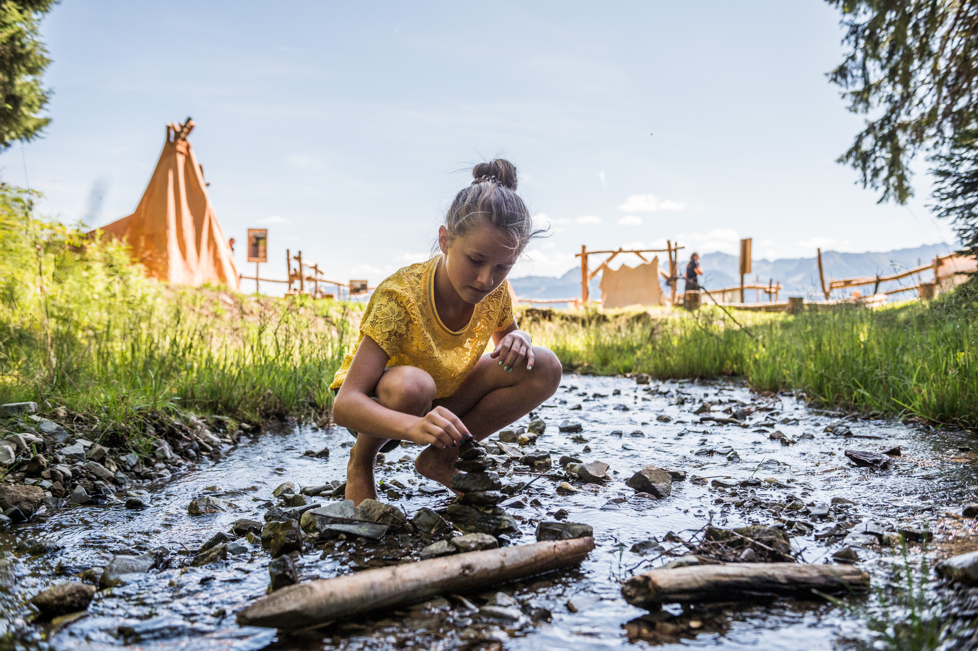 Der Bach im Steinzeitdorf Bolsterlang lädt zum Spielen ein Mädchen sitzt am Bach im Steinzeitdorf Bolsterlang und spielt im Wasser