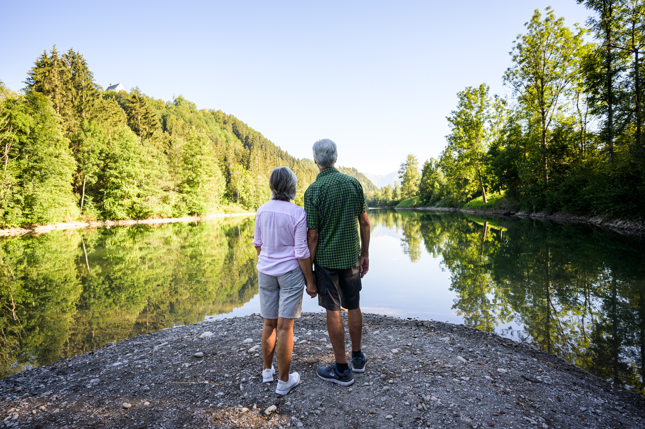 Senioren sehen auf den windstillen Auwaldsee bei Fischen