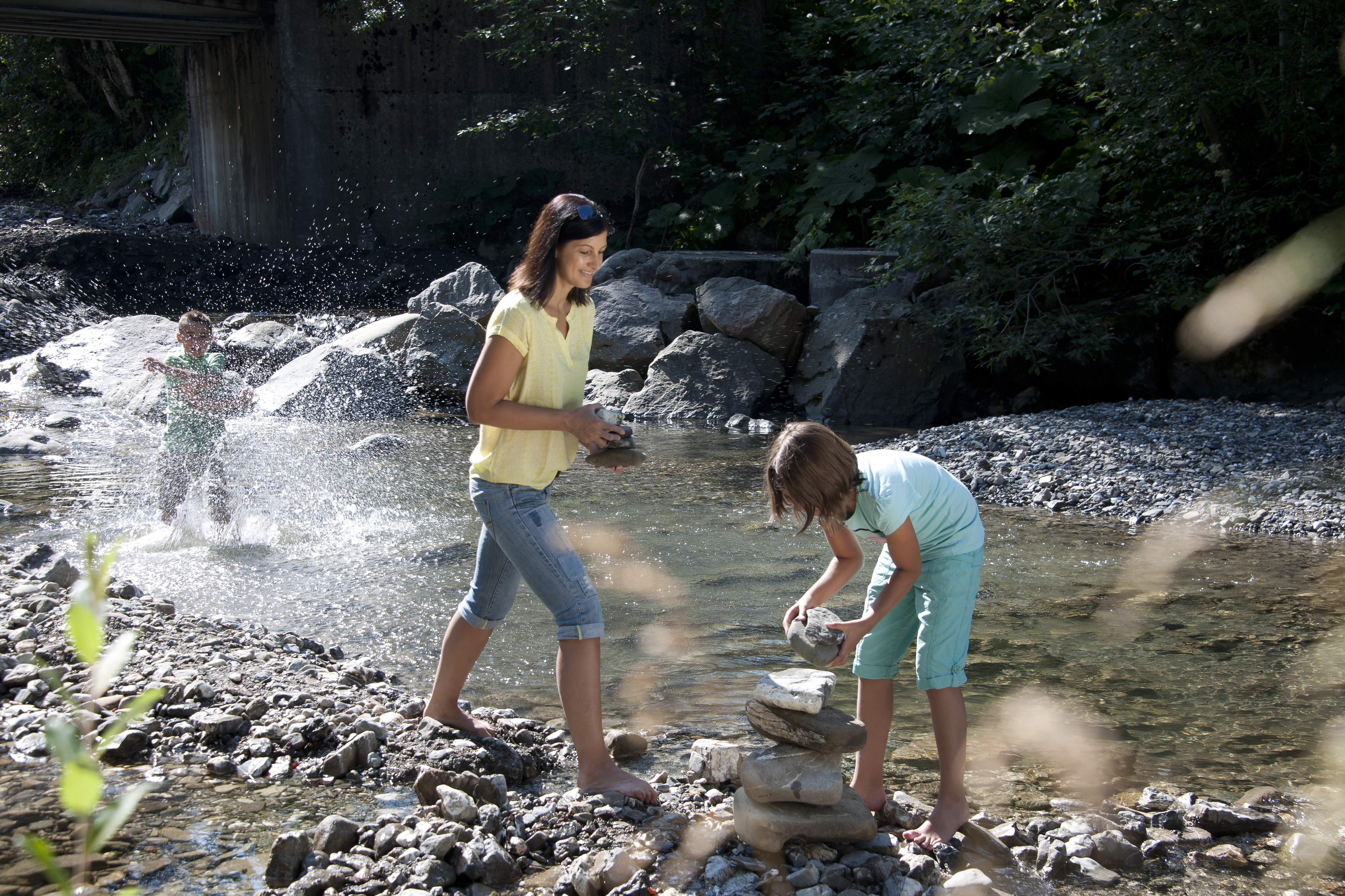 Familie baut Steinmännchen beim Wandern im Bach bei Balderschwang