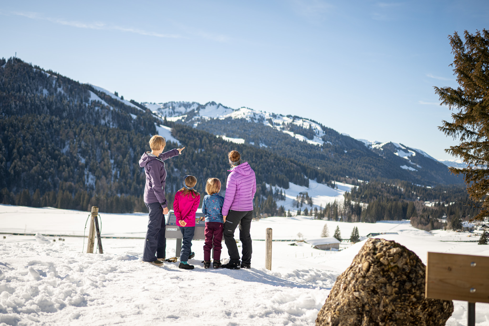 Winterwandern mit Kinden in Balderschwang Familie wandert im Schnee in Balderschwang. Eine vierköpfige Gruppe in Winterkleidung vor einer verschneiten Bergkulisse an einem sonnigen Tag.