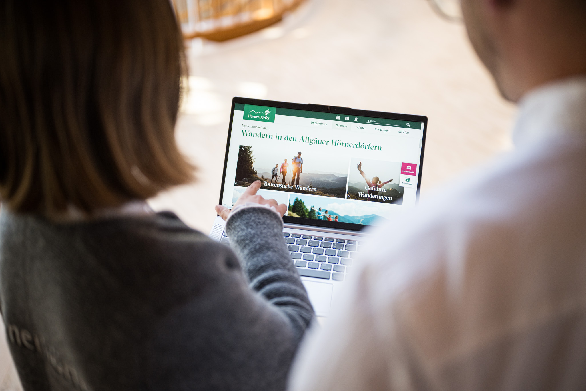 Zwei Mitarbeiter der Tourismus Hörnerdörfer GmbH stellen Webseite am Laptop vor
