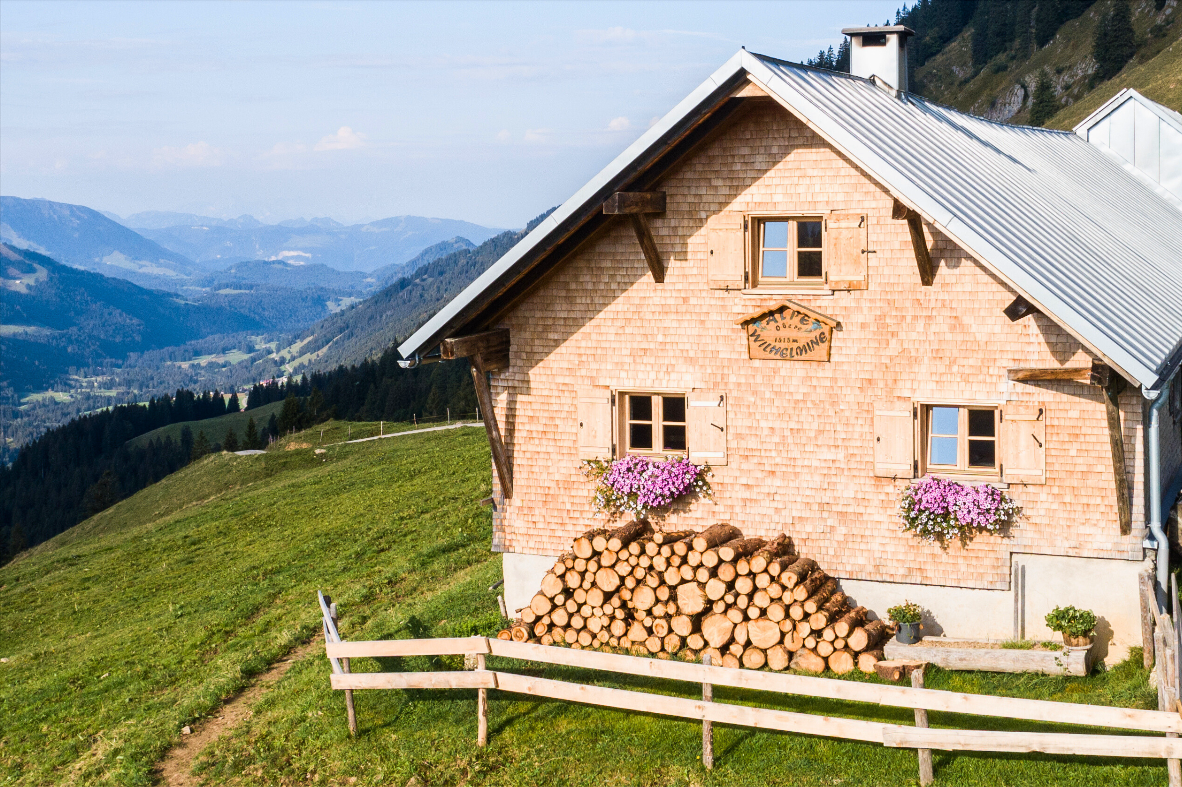 Eine geschindelte Alpe hoch über einem grünen Tal in der Allgäuer Alpen