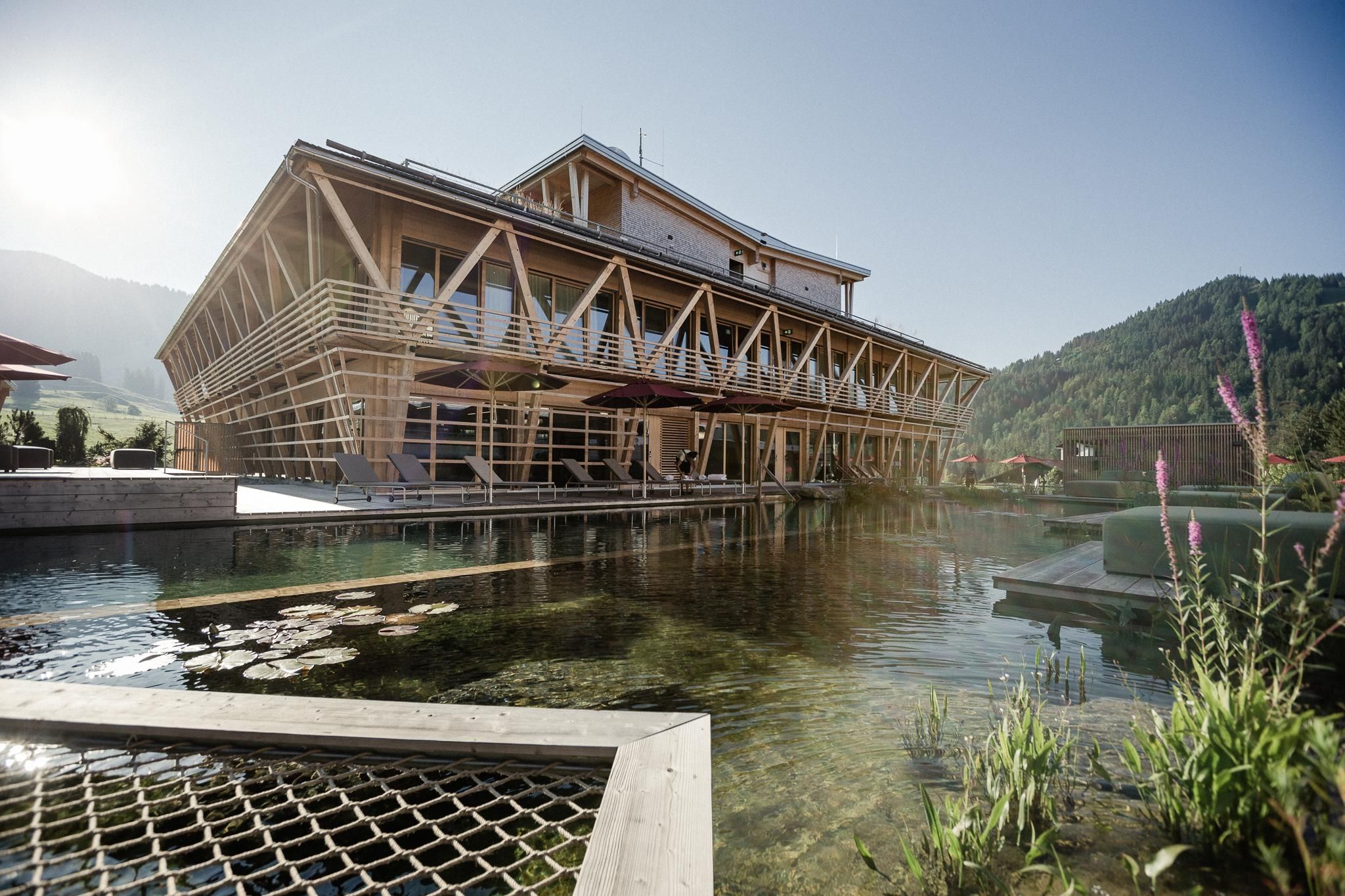 Modernes Holzgebäude am Rande eines natürlichen Schwimmteichs.