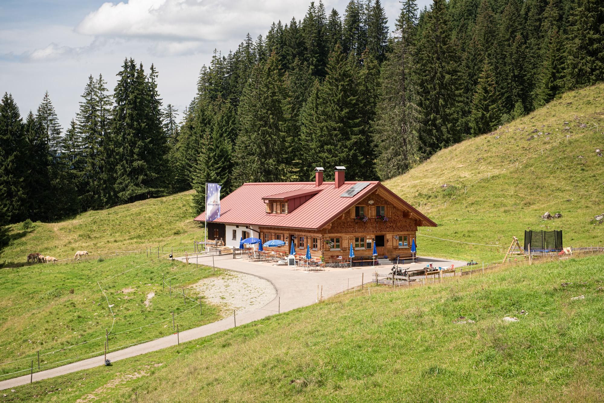 Eine charmante Alpe in einer grünen Landschaft umgeben von Bäumen. Die ruhige Umgebung lädt zum Entspannen ein.