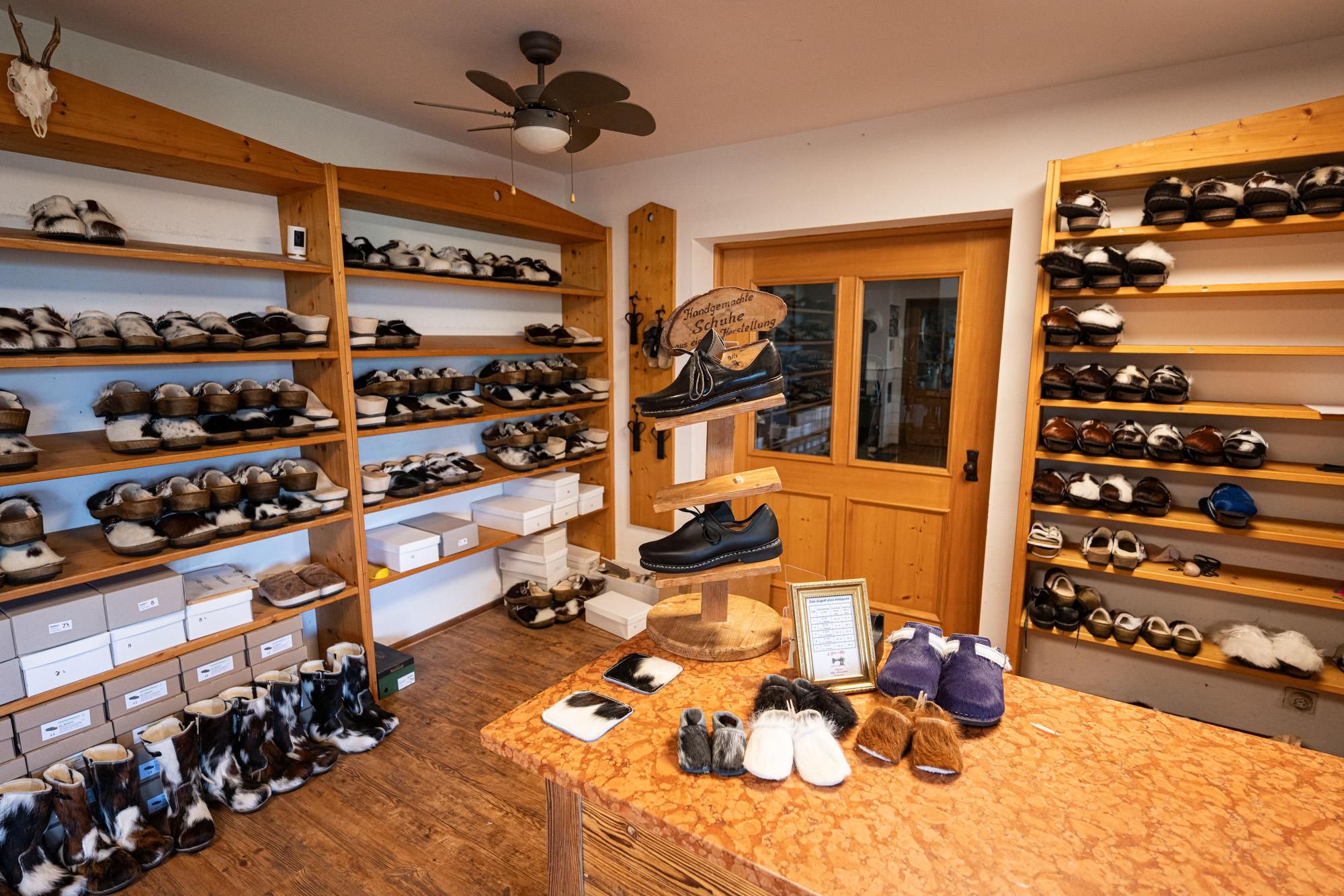 Schuhgeschäft mit hölzernen Regalen voller Filzschuhe, ein Verkaufstisch mit verschiedenen Modellen und ein Holzschild "Schuh Keller".