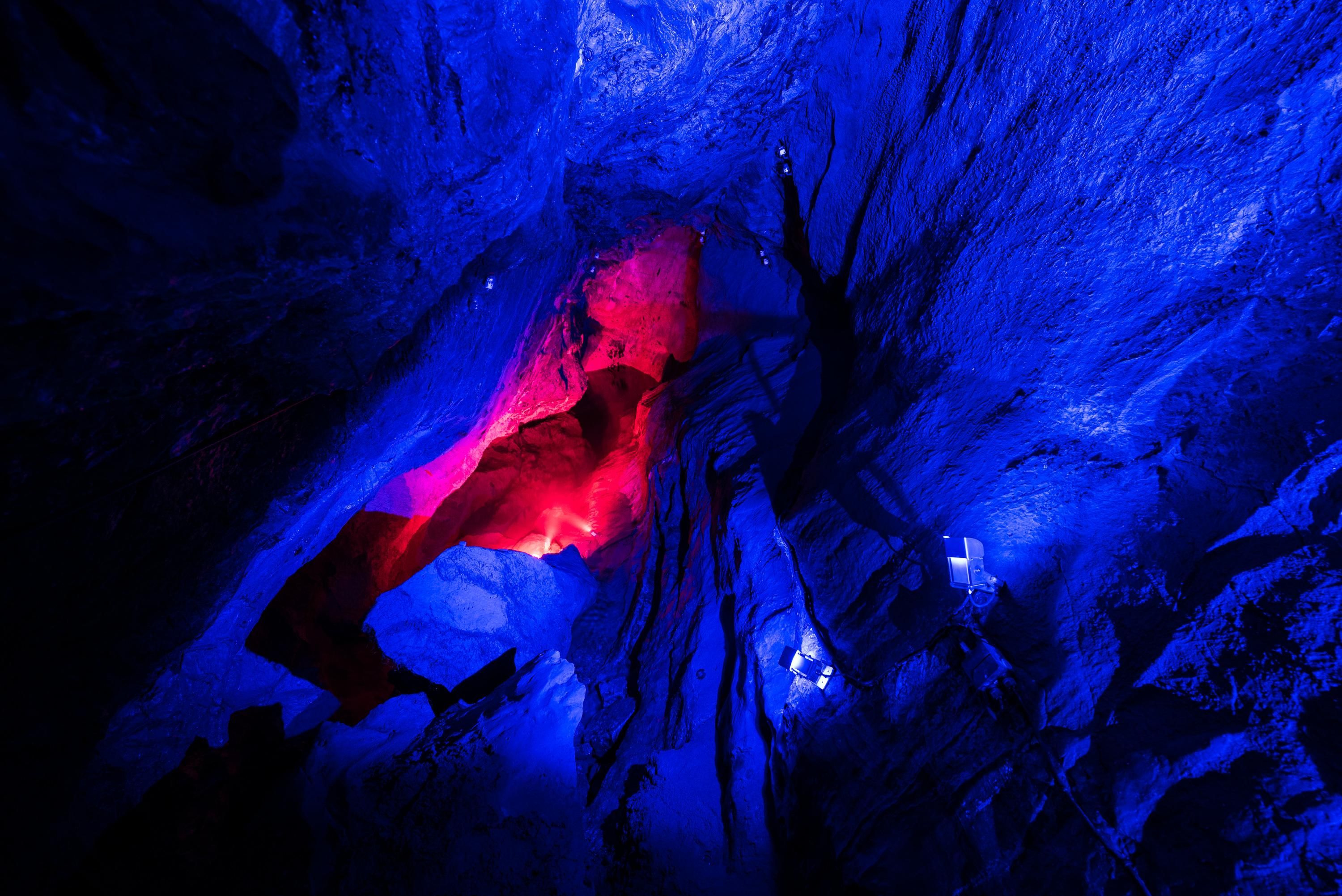 Eine rote und blaue Lichtinstallation in der Sturmannshöhle erhellt die Felswände, die die Gruselführung hervorhebt.