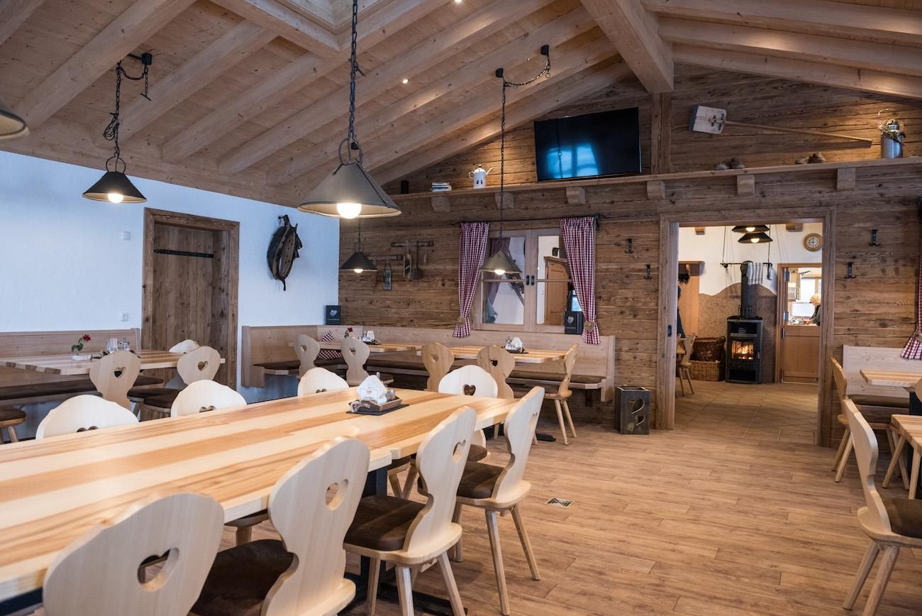 Im Inneren der Leitenbach Hütte sind Holztische und Stühle aufgestellt, die ein rustikales und einladendes Esserlebnis bieten.