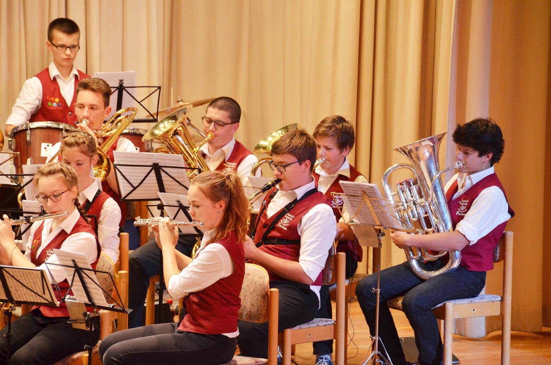 Einige Teilnehmer*innen des Jugendblasorchesters Fischen, alle bekleidet mit weißen Hemden und roten Westen.