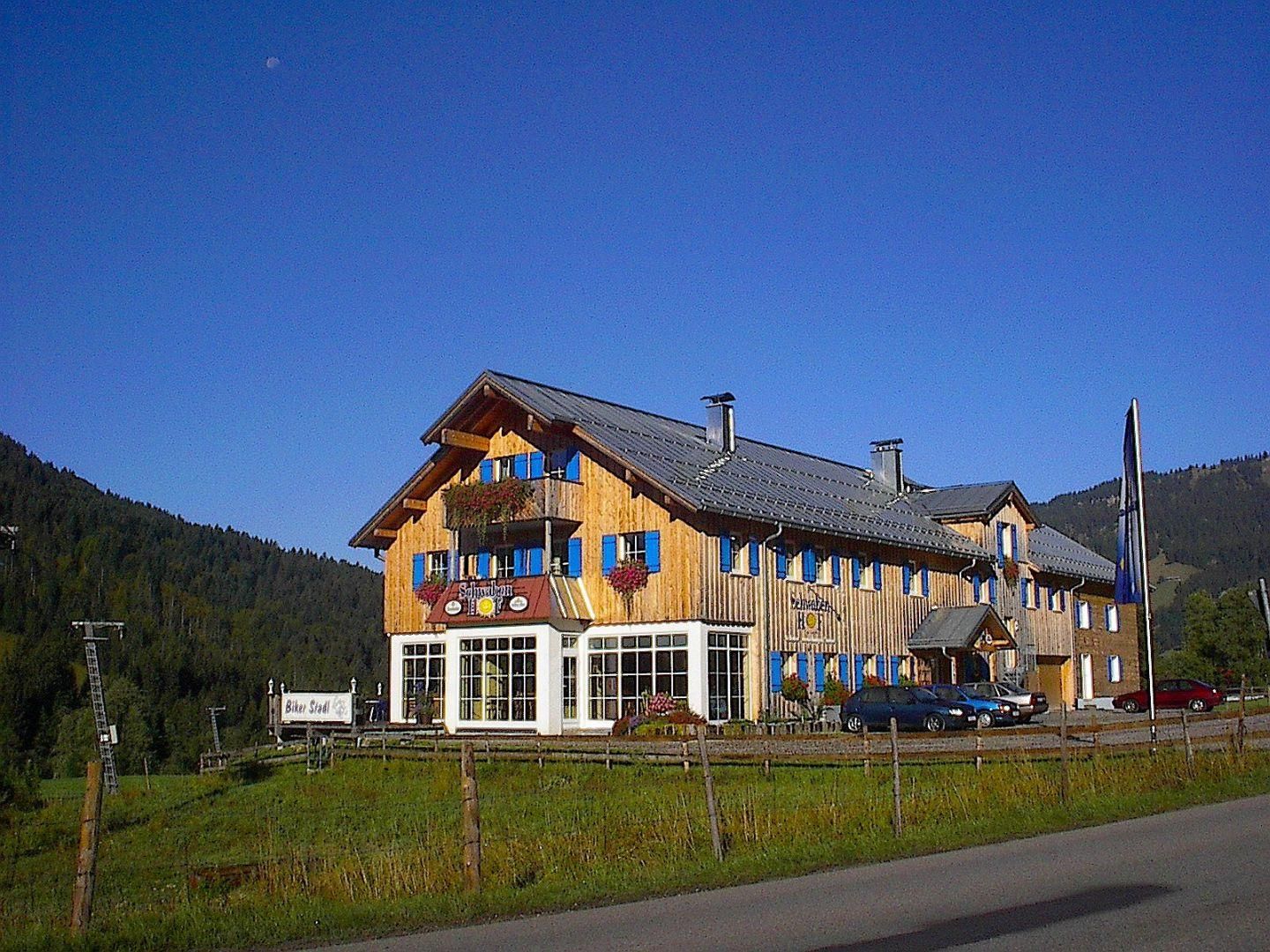 Alpengasthof Schwabenhof in Balderschwang, Berghütte mit blauen Fensterläden, sonniger Tag.