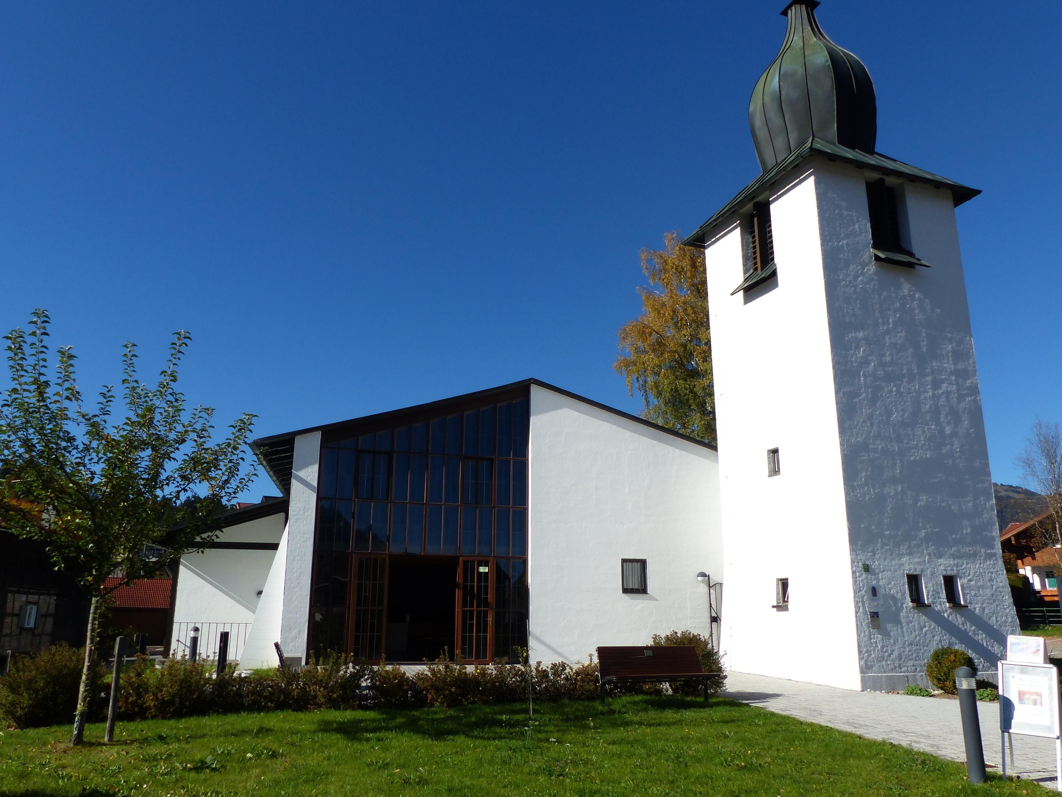 Die Evangelische Kirche im Sommer, Gras und Bäume sind saftig grün.
