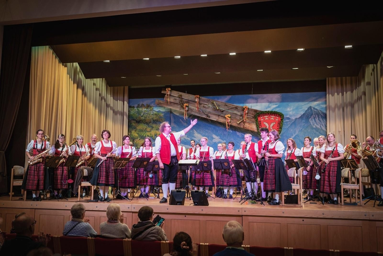 Das Ende eines Auftritts der Musikkapelle Fischen im Kurhaus Fiskina, der Dirigent zeigt auf die stehenden Musiker*innen.