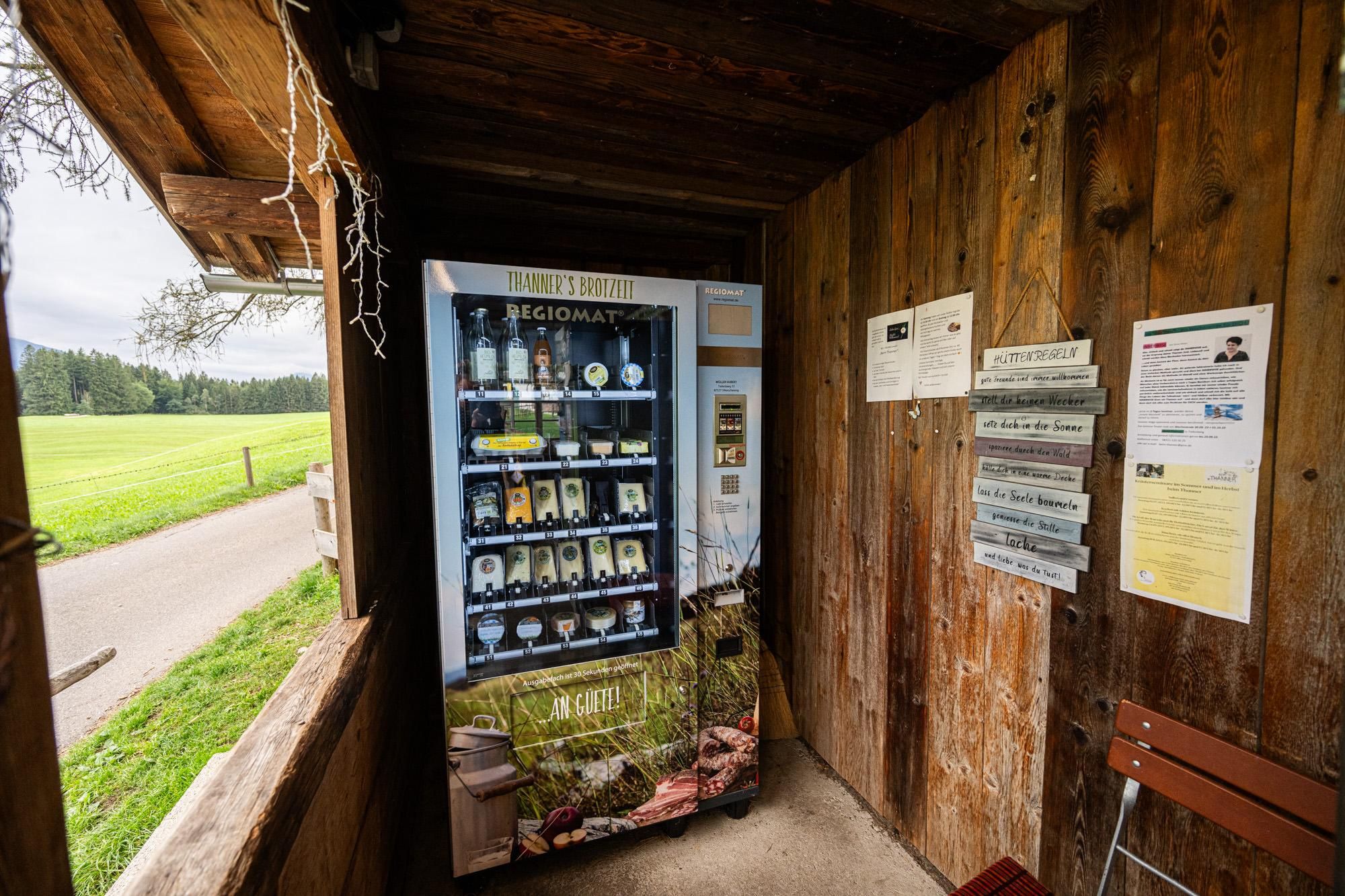 Milchtankstelle "Beim Thanner": Gekühlter Automat mit regionalen Produkten, Holzverkleidung, Hinweisschilder an der Wand.