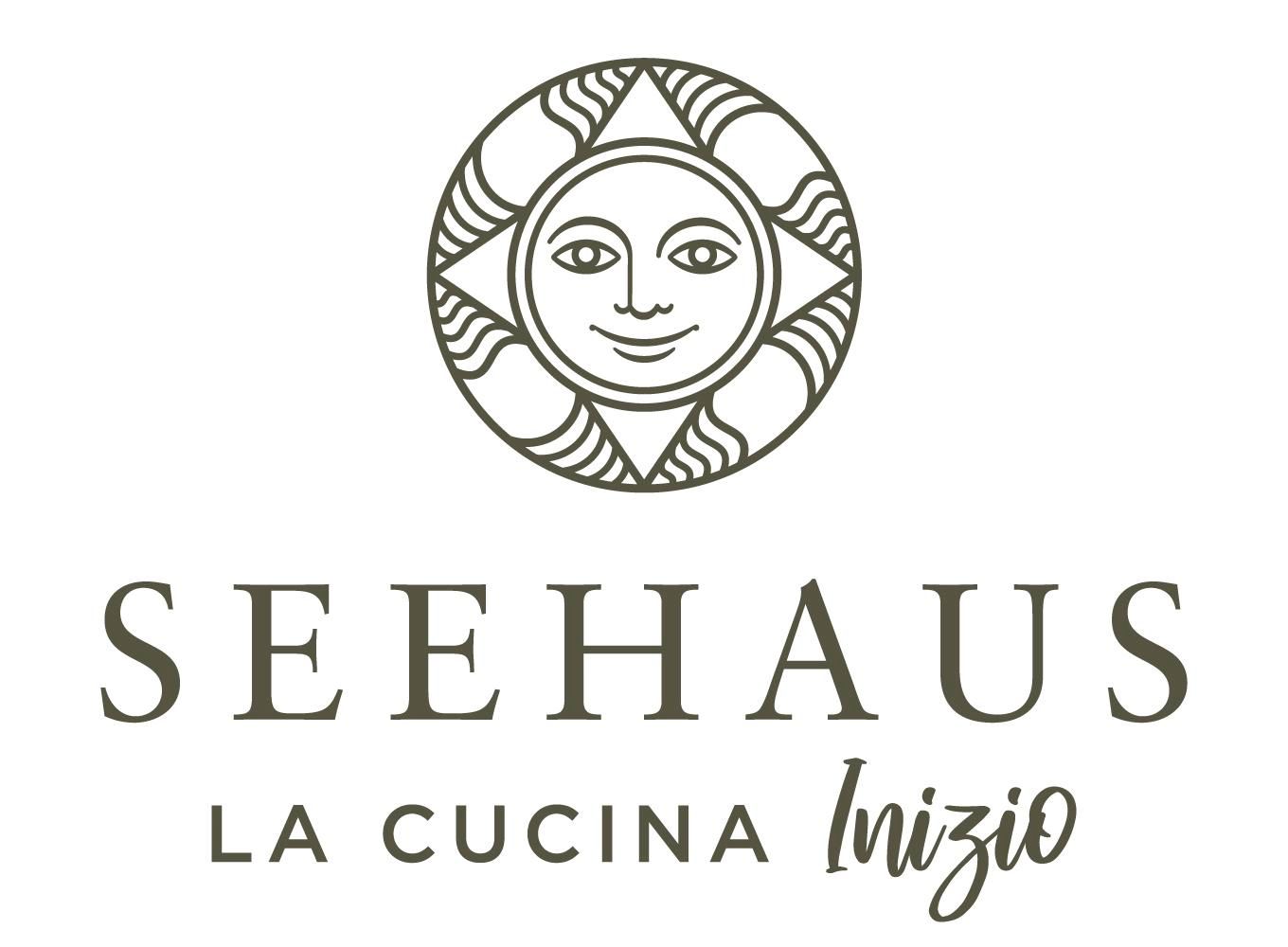 Logo "Seehaus - La Cucina Inizio": Ovale Sonne mit Gesicht und Strahlen. Darunter der Schriftzug "SEEHAUS". Darunter "LA CUCINA" links und kursiv "Inizio" rechts.