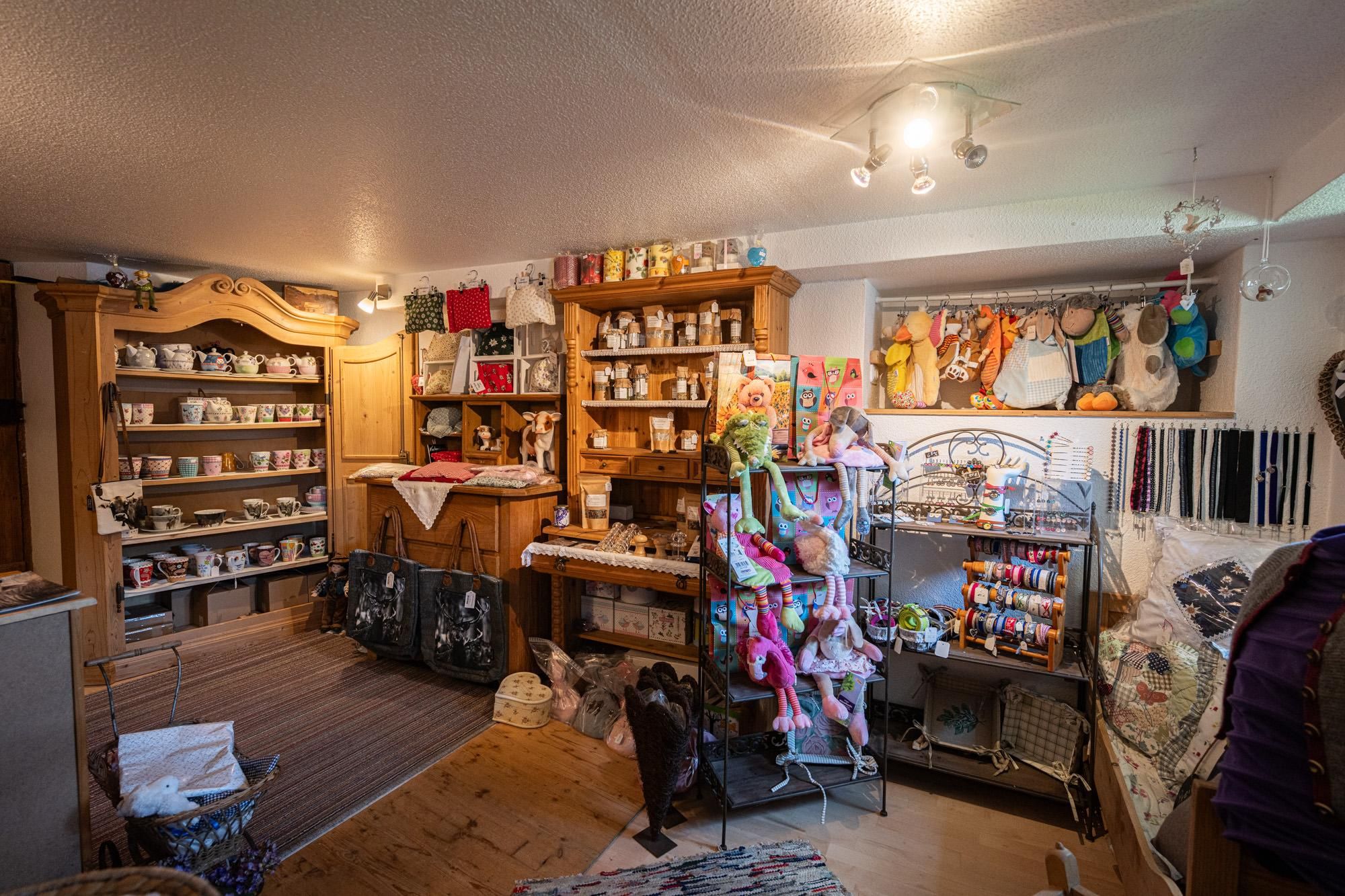 Gemütlicher, kleiner Laden in Obermaiselstein. Holzregale gefüllt mit Tassen, Gewürzen und Geschenkartikeln.