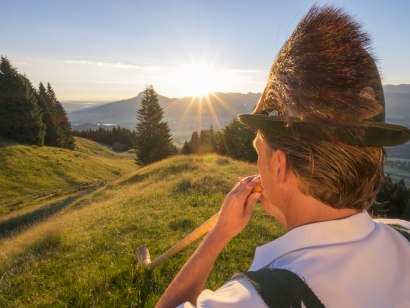 Alphornspieler in der aufgehenden Morgensonne am Ofterschwanger Horn. Gelebte Tradition im Allgäu., © Tourismus Hörnerdörfer