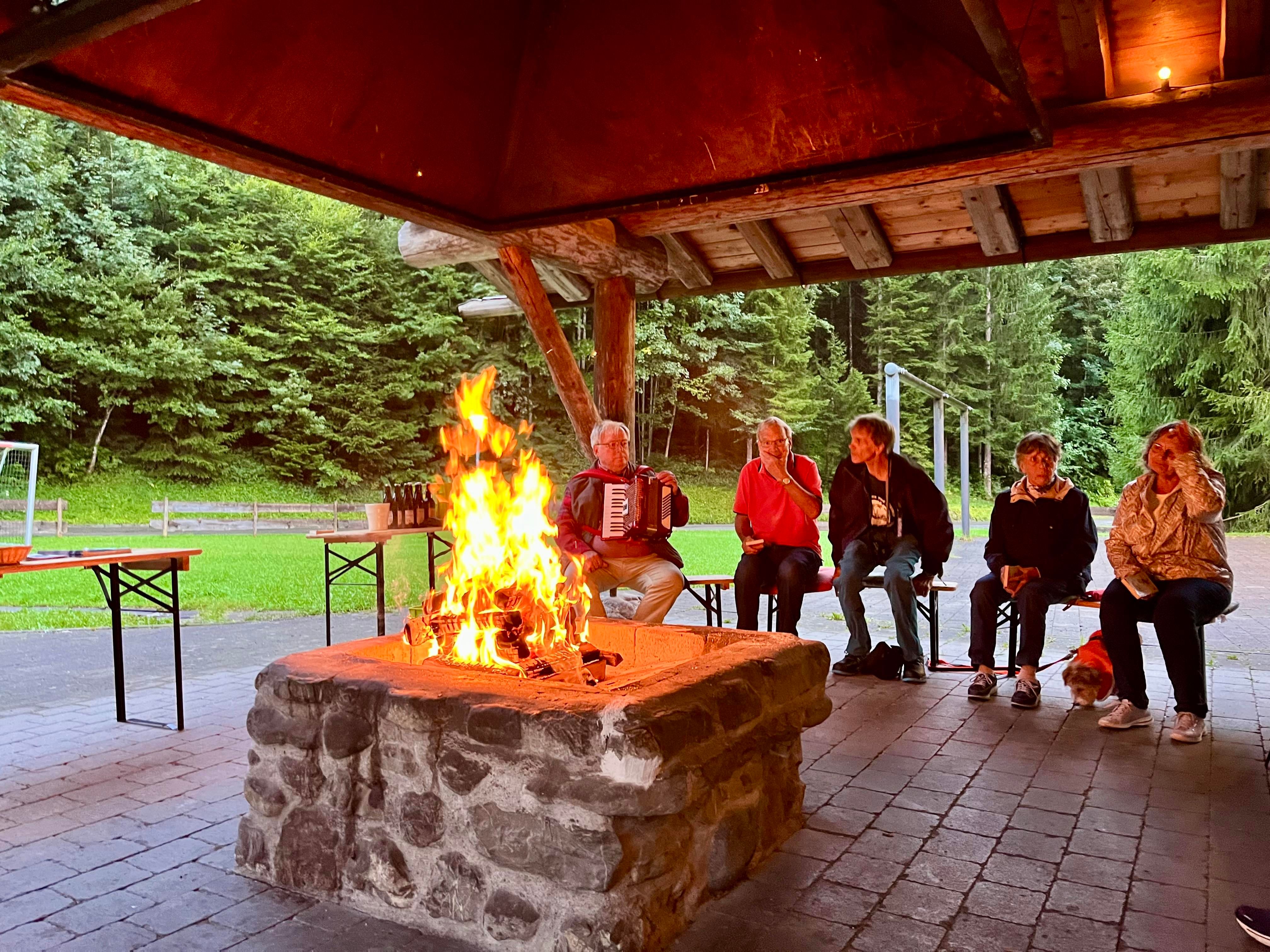 Eine Gruppe von Menschen sitzt um ein Lagerfeuer.