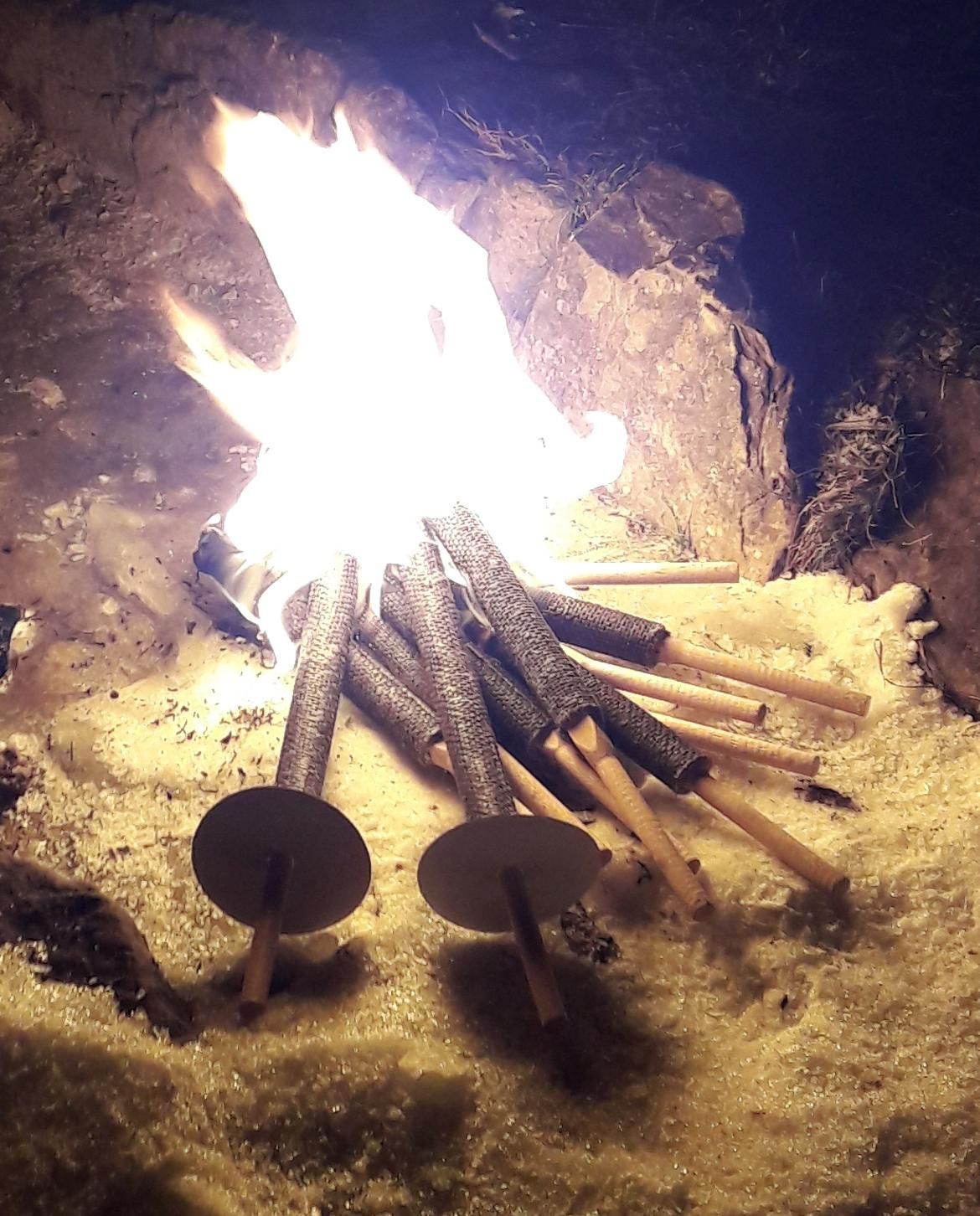 Etliche Fackeln liegen hier brennend auf einem Haufen im Schnee.