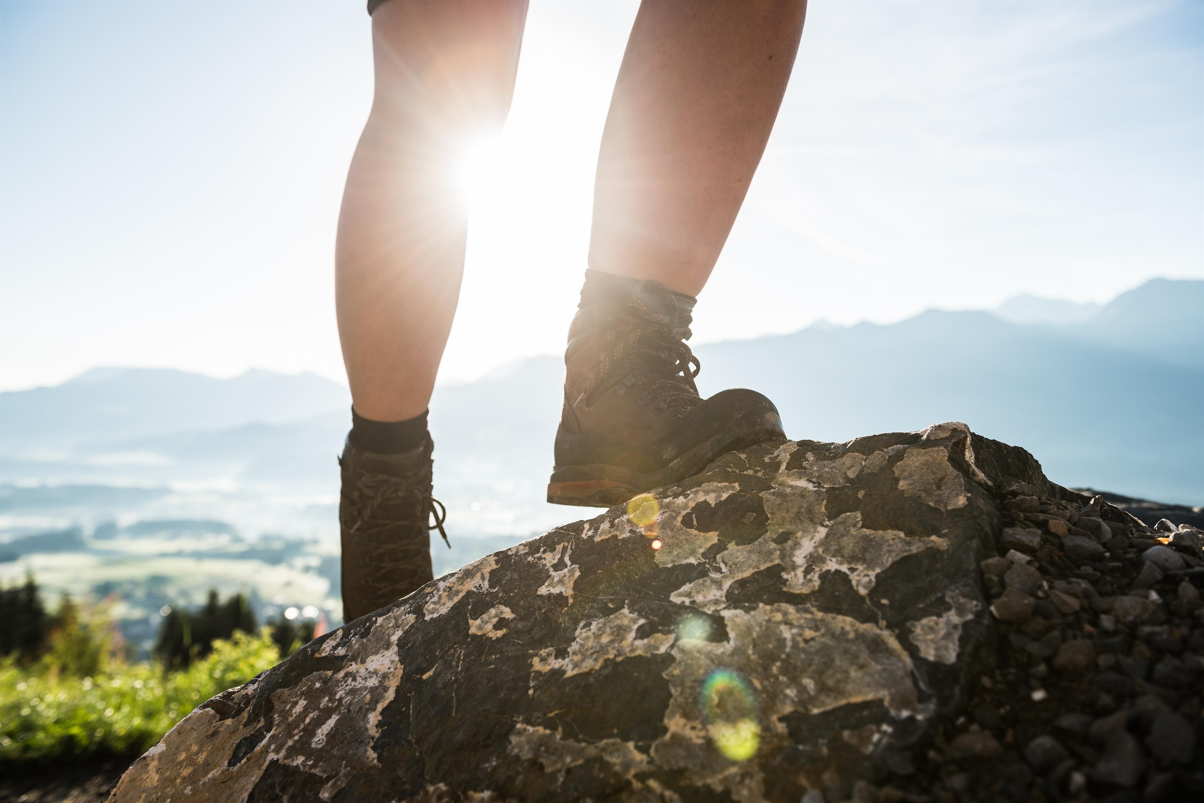 Eine Person läuft mit Bergstiefeln über einen Felsen, man siehr nur die Beine.