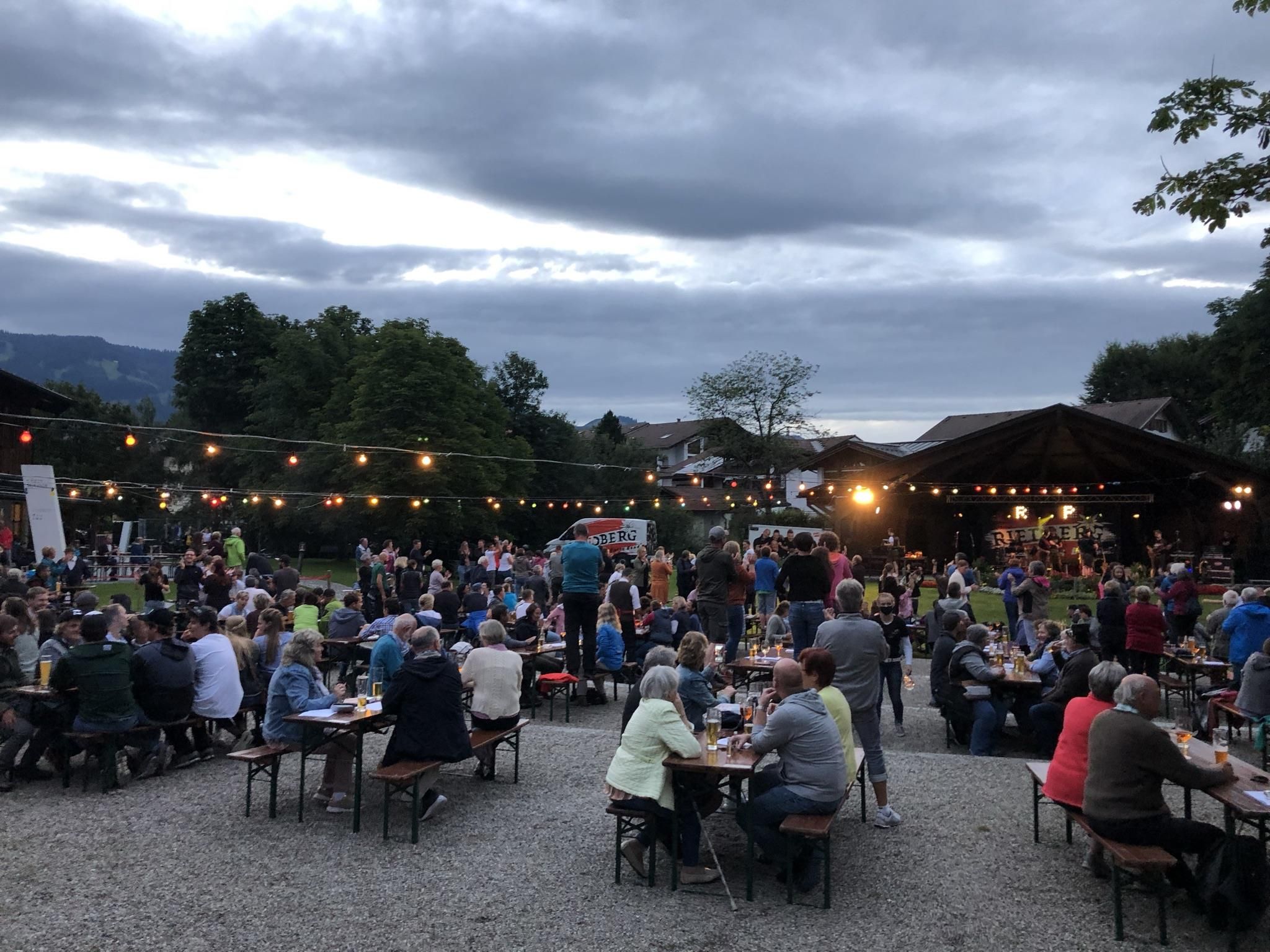 Musikpavillon vor Kurhaus, viele Menschen sitzen an Bierzelttischen, Getränke vor sich, die Band spielt.