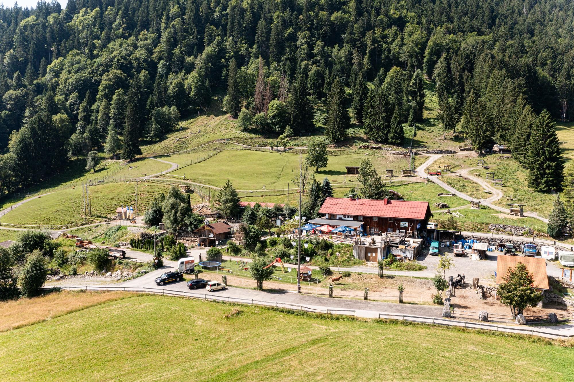 Der Alpenwildpark Obermaiselstein von oben: ein weites Gelände mit Wald, Wiesen, Gehegen und dem Berghof Schwarzenberg.