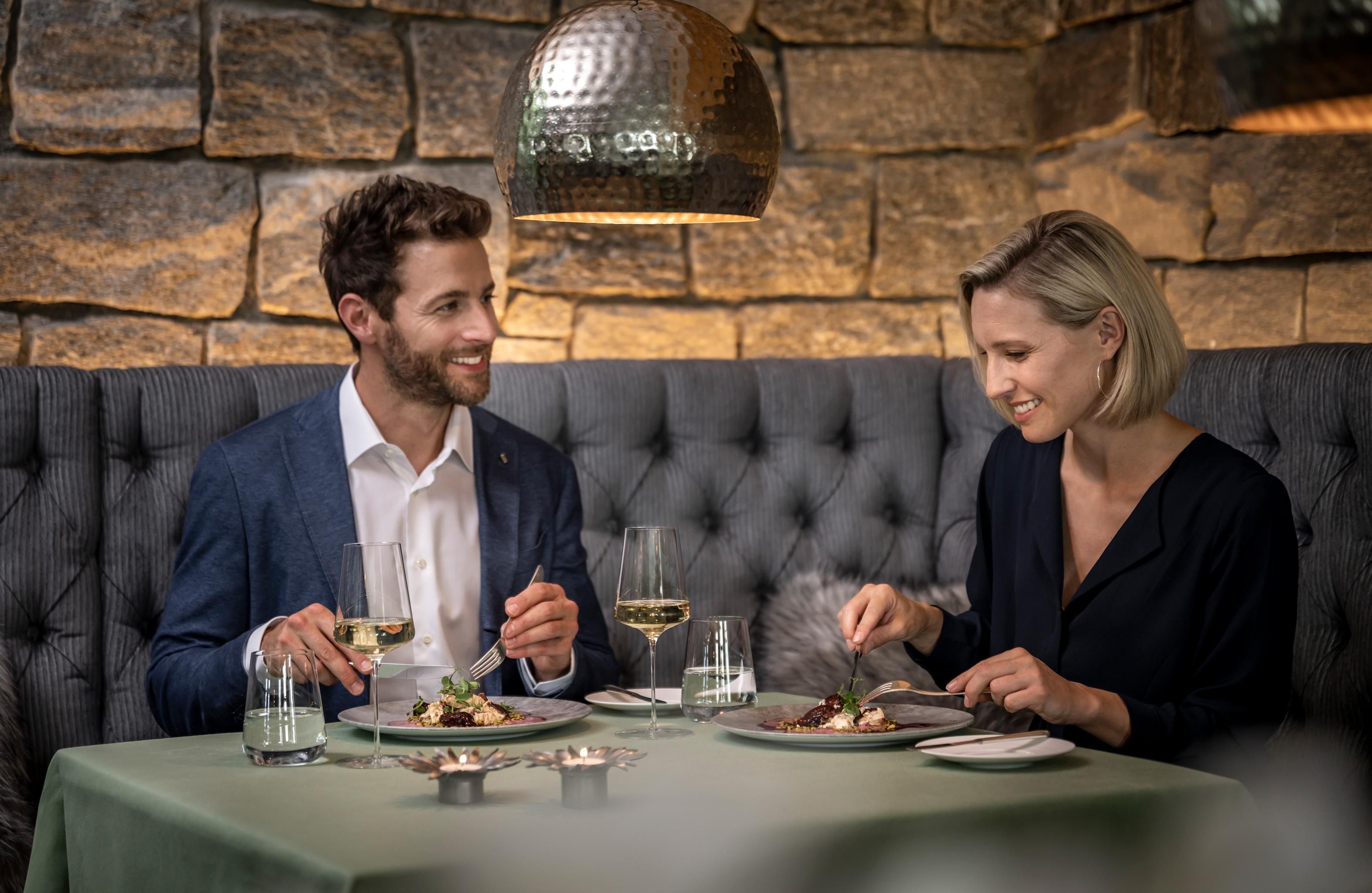 Ein Paar sitzt bei einem Abendessen im Gourmetrestaurant im Sonnenalp Resort.