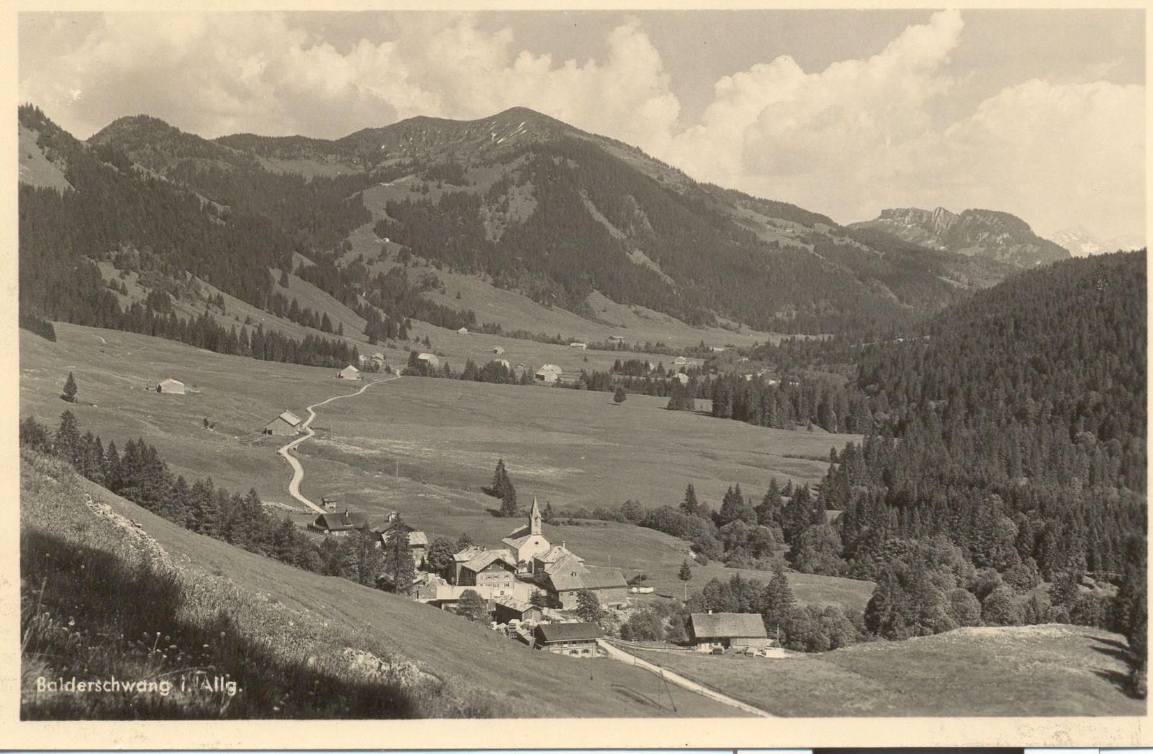 Historische Aufnahme von Balderschwang im Allgäu. Ein kleines Dorf mit einer Kirche liegt eingebettet in eine weite, grüne Berglandschaft. Dunkle Wälder bedecken die Hänge.