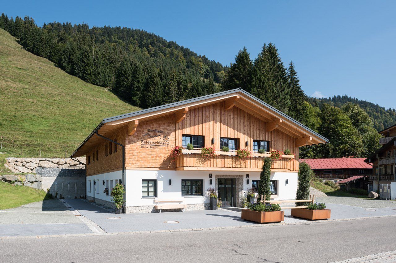 Das Dorfhaus in Balderschwang - ein schönes Allgäuer Haus mit Balkon und großen Fenstern. Ebenerdiger Eingang vorne. Balderschwanger Berge im Hintergrund.