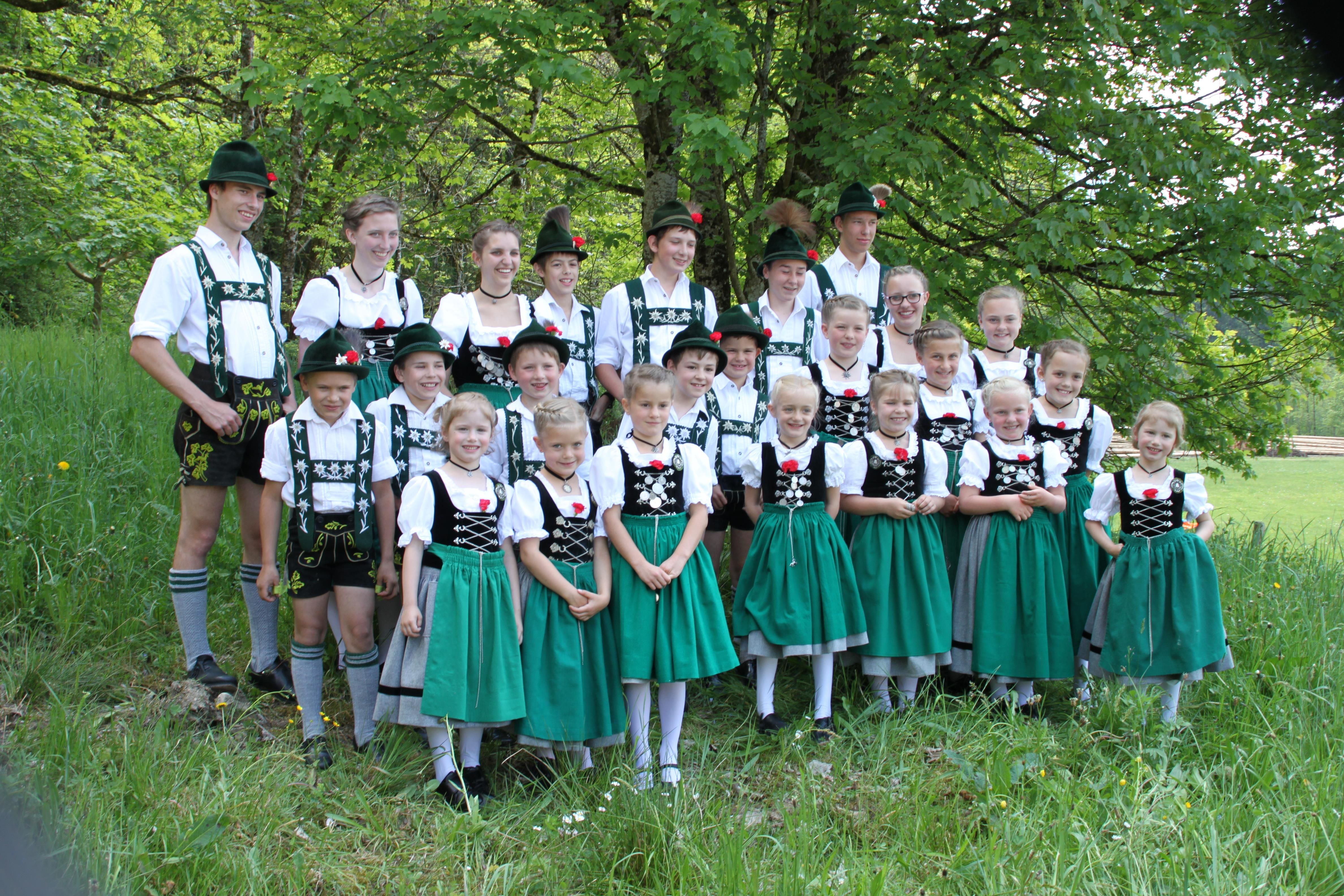 Kinder und Jugendliche des Trachtenvereins, die Jungen tragen kurze Lederhosen, die Mädchen Dirndl mit grünen Schürzen.