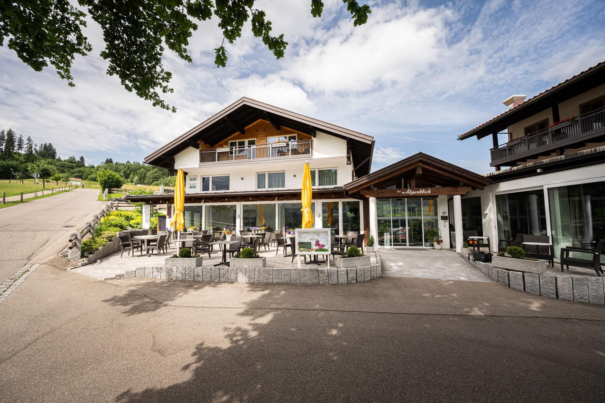 Ein charmantes Hotel-Restaurant mit modernen Gebäuden und gemütlichen Terrassen. Umgeben von grünen Landschaften und blauen Himmel.