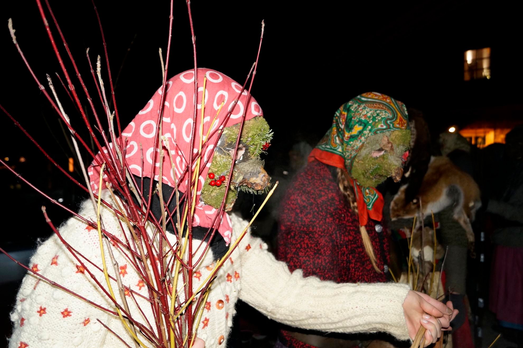 Zwei als Bärbele verkleidete Gestalten mit Masken und Kopftüchern, halten Ruten in den Händen.