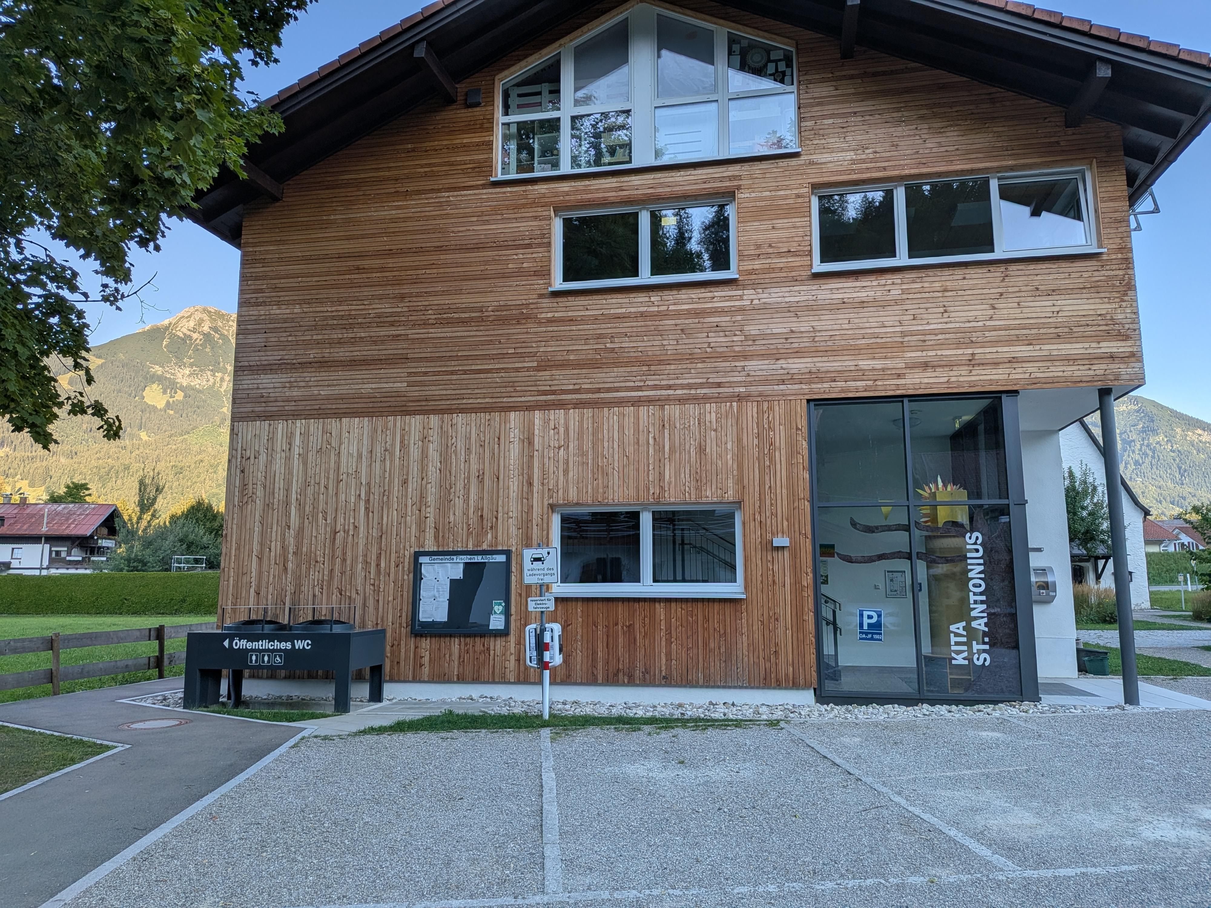 Parkplätze mit Ladestation für E-Autos vor einem Haus mit Holz verkleidet.