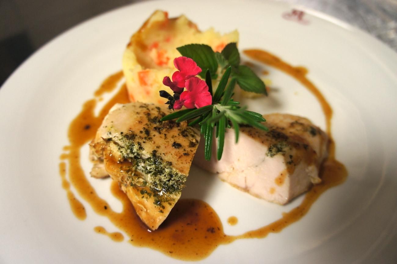 Fein angerichtetes Geflügelgericht auf einem weißen Teller.