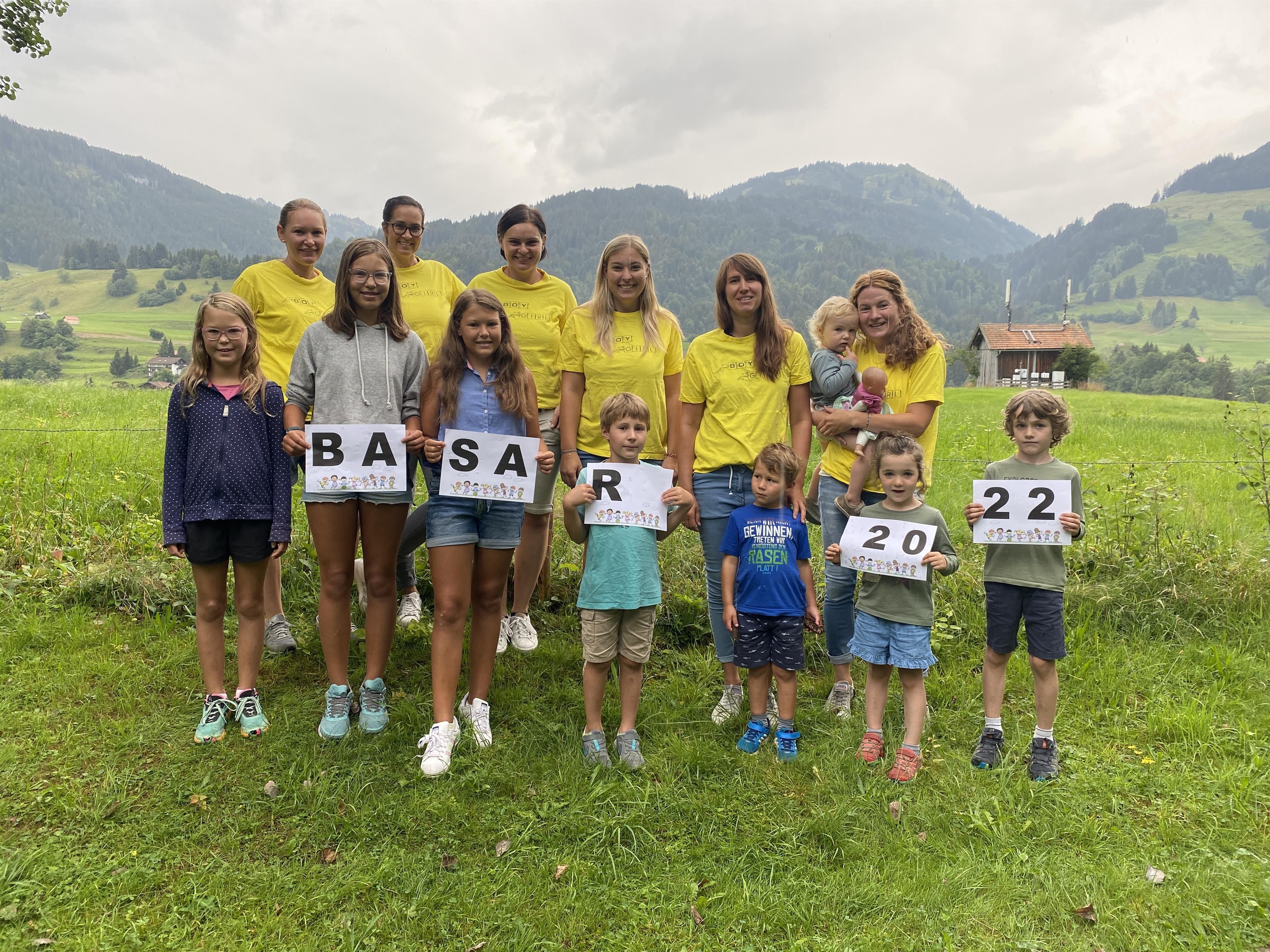 <p>Gruppe von dreizehn lächelnden Frauen in gelben T-Shirts stehen in einer Halle.</p>