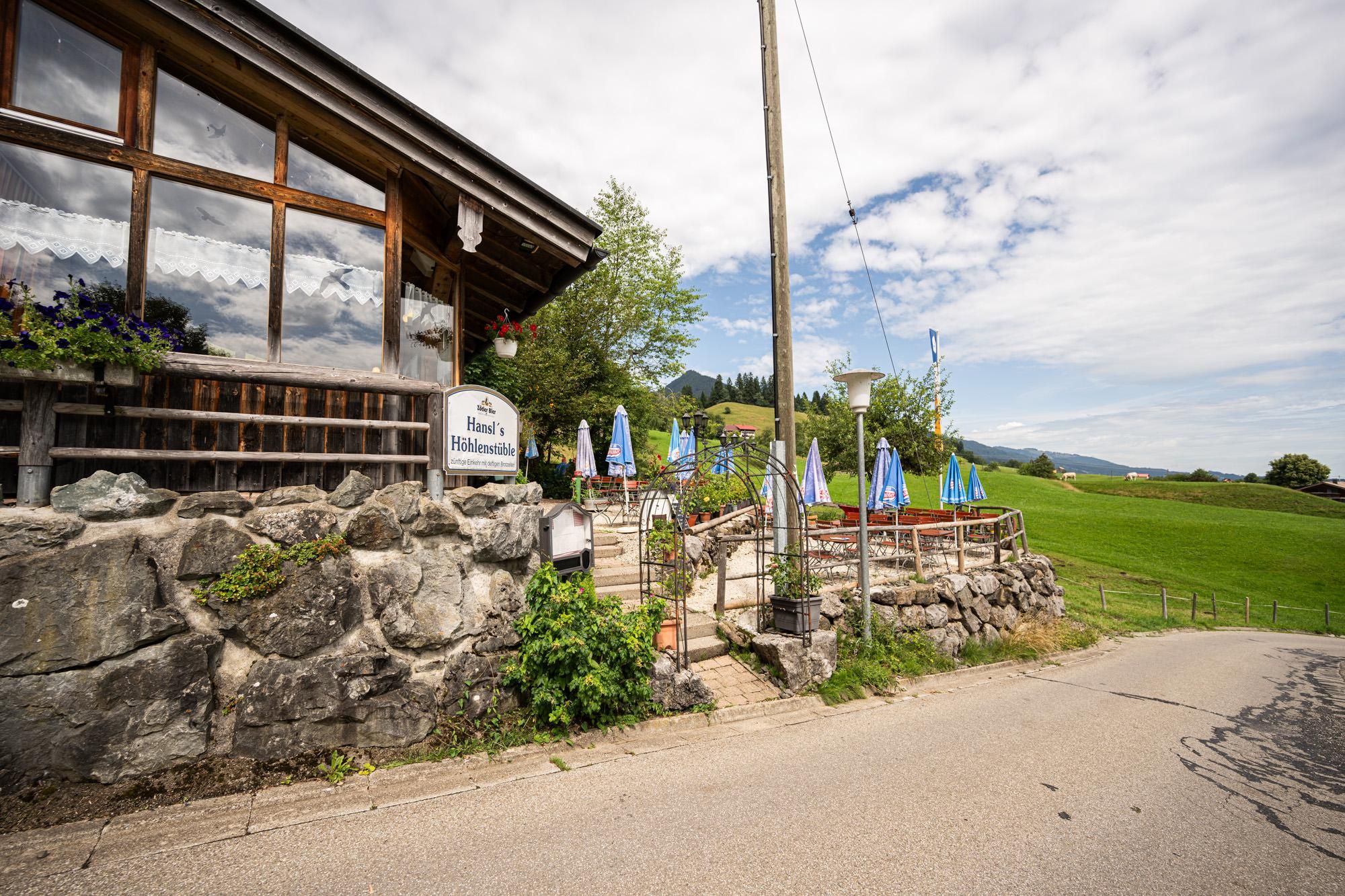 Außenansicht des Restaurants Höhlenstüble mit großer Fensterfront und Holzbalkonen. Ein Schild mit der Aufschrift "Höhlenstüble Restaurant" ist sichtbar.