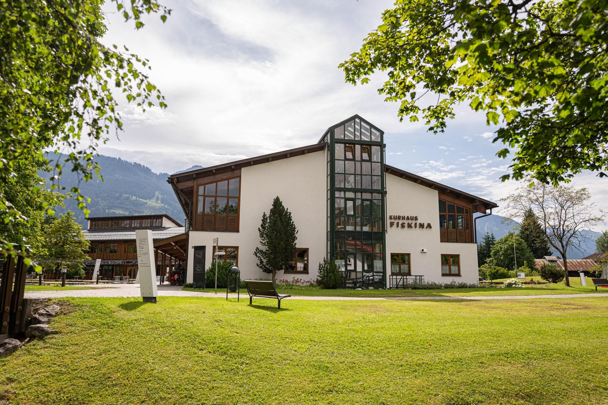 Das Kurhaus Fiskina vom Kurpark aus zwischen Kastanienbäumen und viel Wiese.