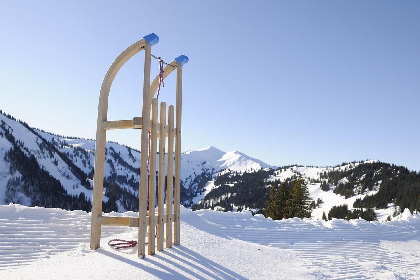 Holzschlitten vor einer winterlichen Berglandschaft