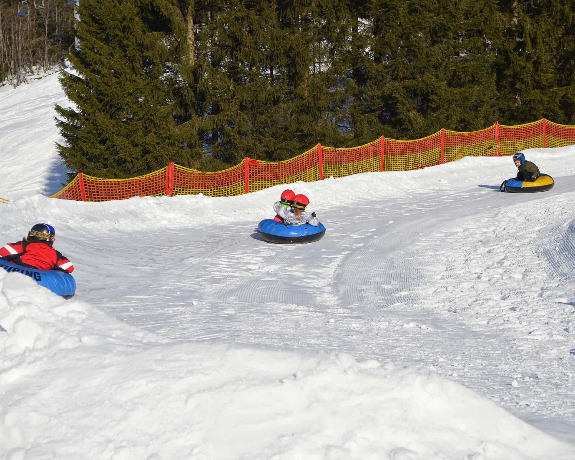 Kinder rodeln mit Reifen die vorpräpariete Snowtube Piste hinunter