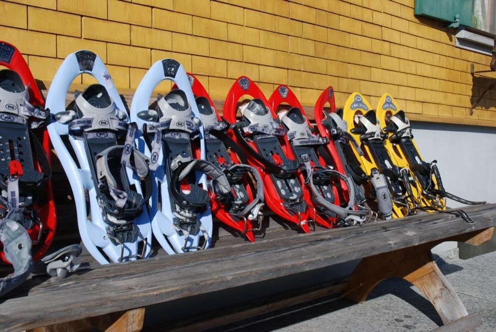 Aufgereihte Schneeschuhe an einer Hütte