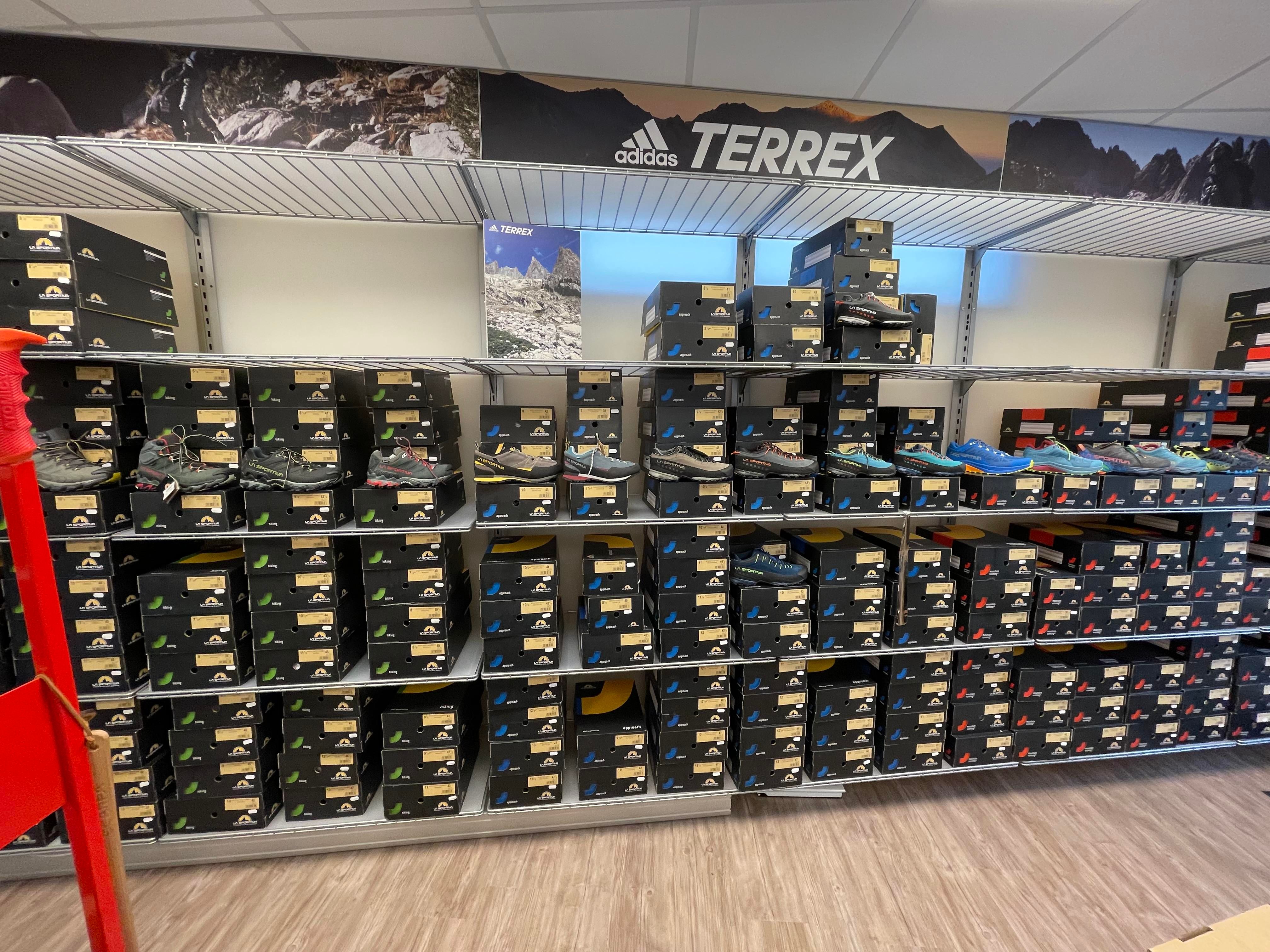 Schuhregal mit Sportschuhen und Schuhkartons. Marke Adidas Terrex sichtbar. Unterschiedliche Modelle und Farben.