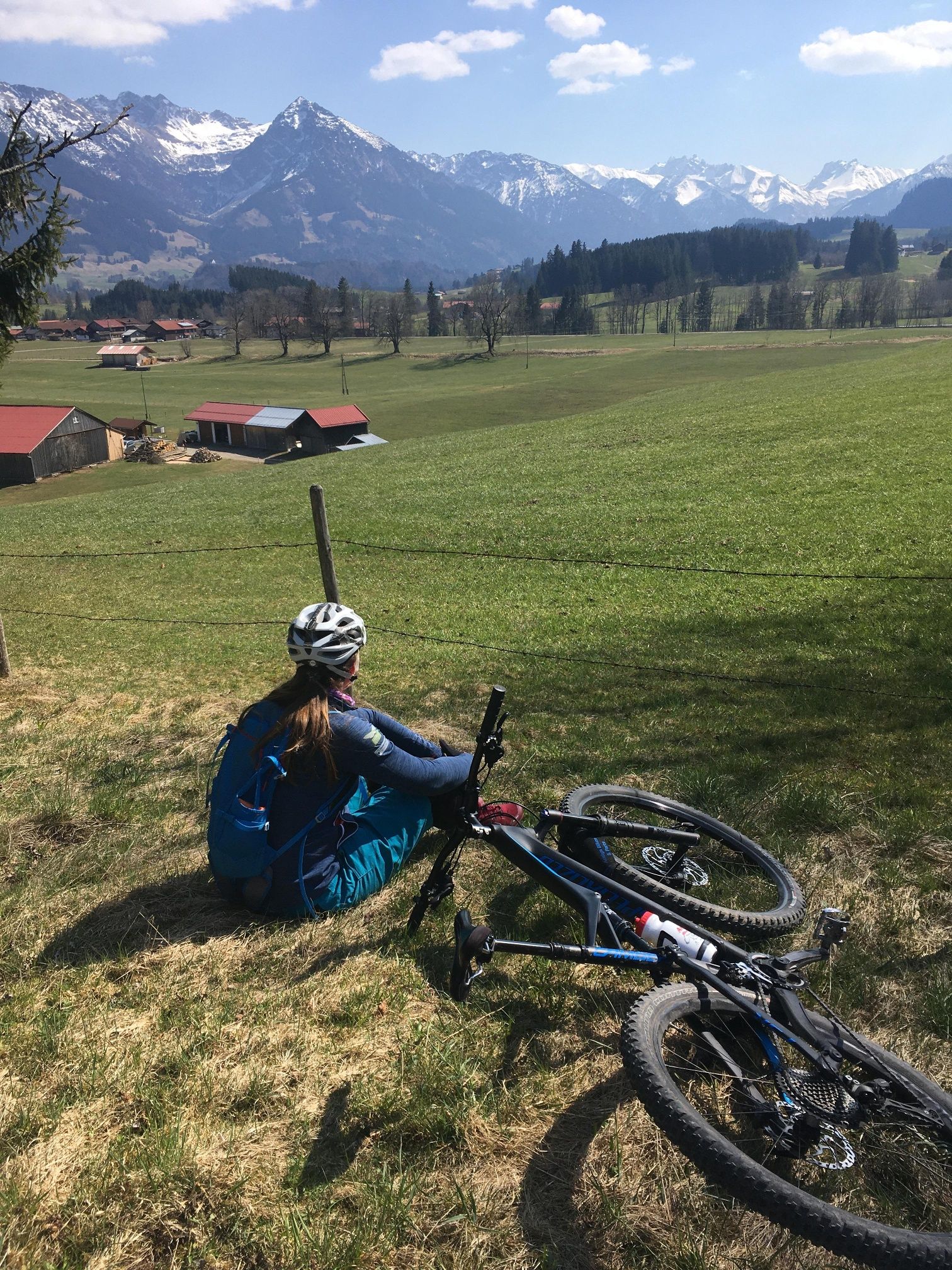 Radfharer bei Rast auf Wiese mit Blick auf die Alpenkulisse